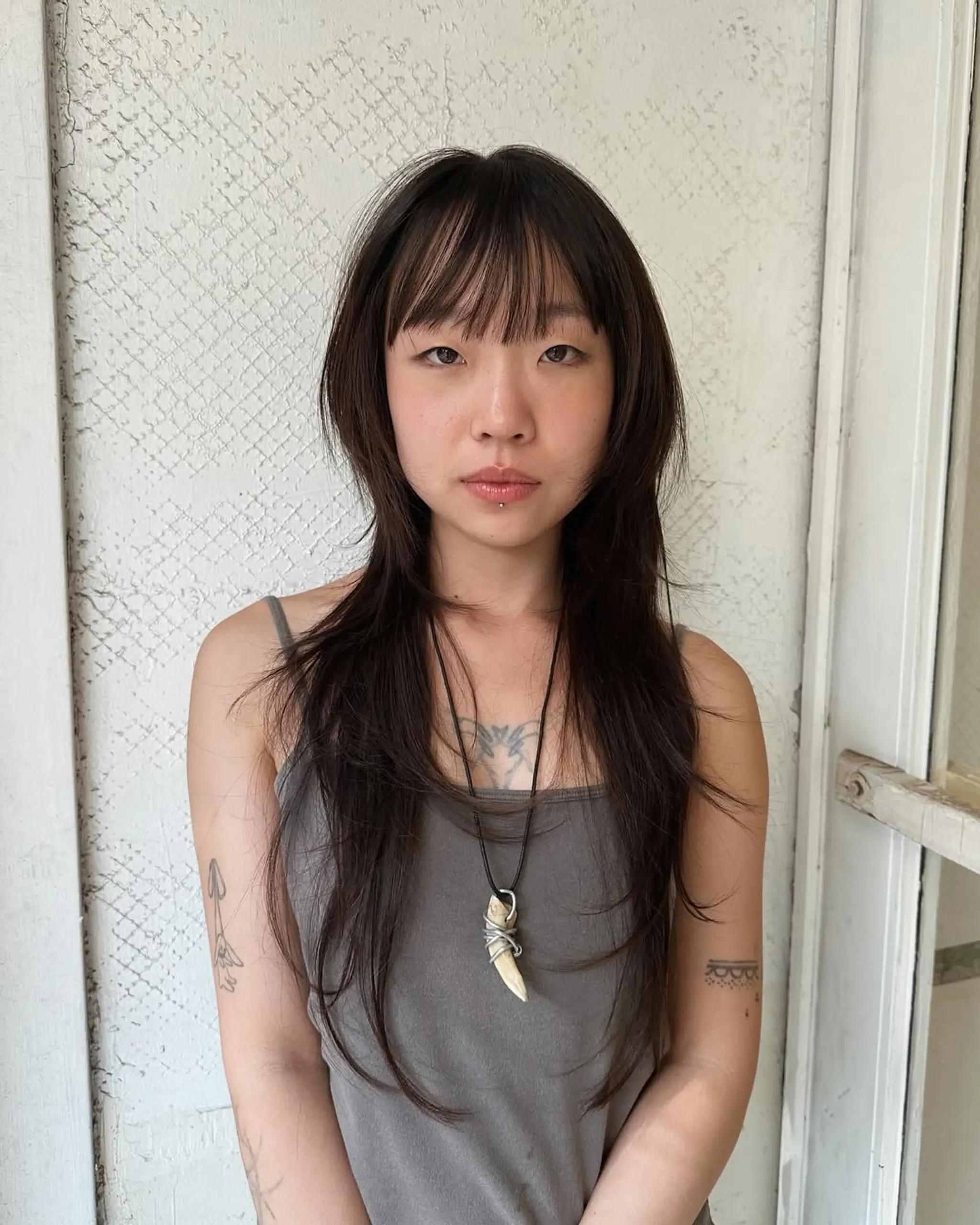 Long, straight dark hair with layered lengths and wispy fringe, featuring long side bangs and tapered ends.