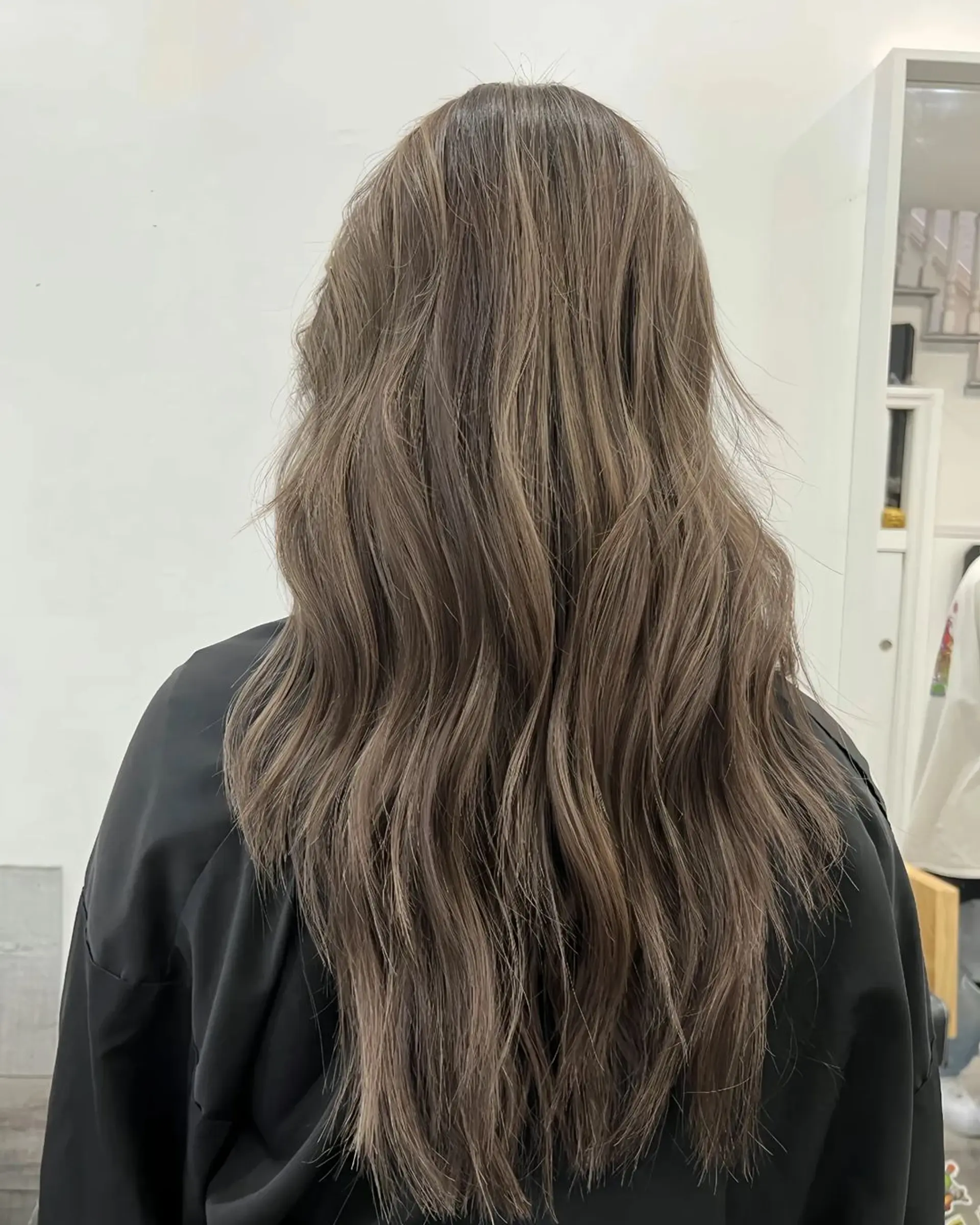 Long, light brown hair with ash brown highlights, styled in loose, natural waves with a layered cut. 1