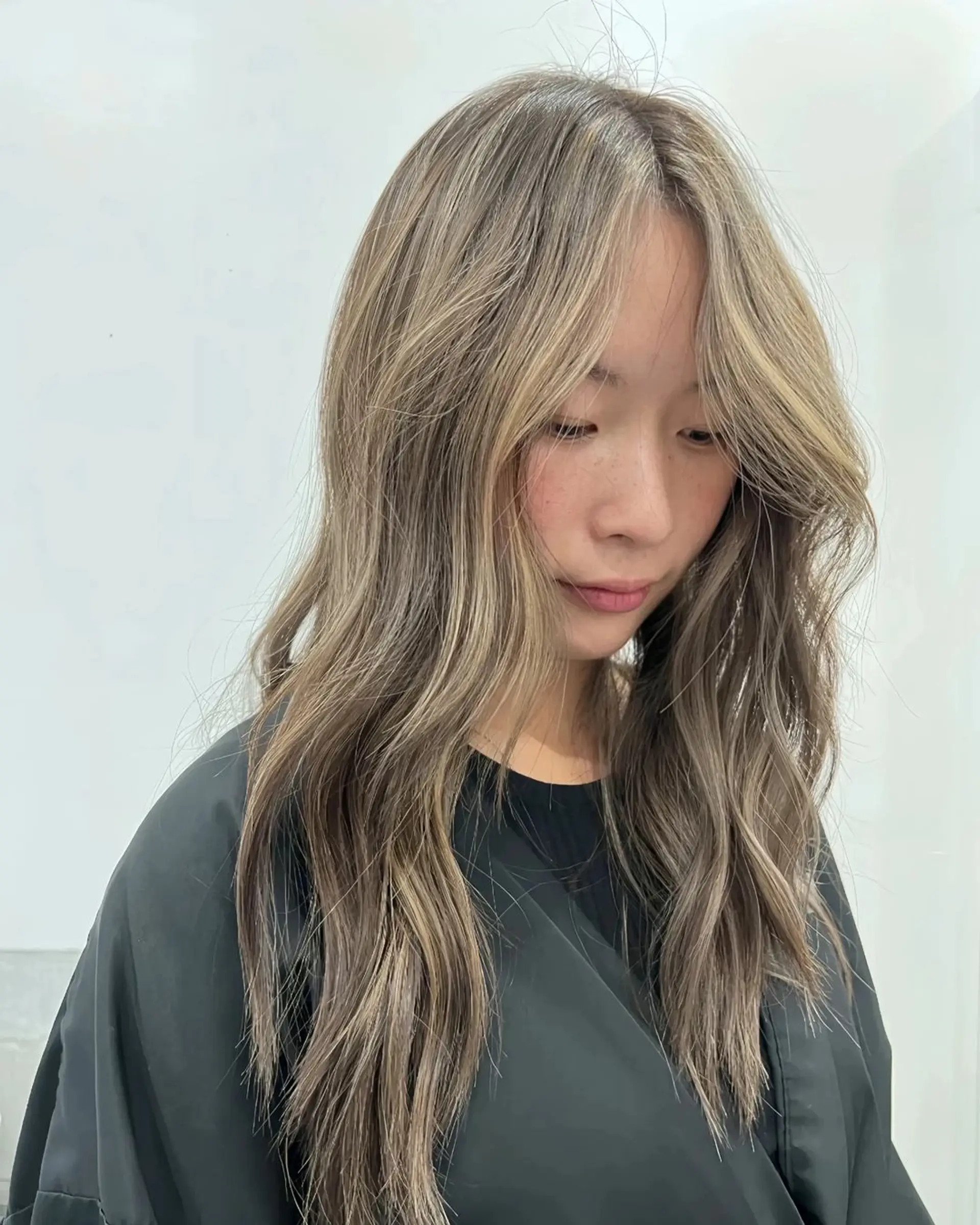 Long, light brown hair with ash brown highlights, styled in loose, natural waves with a layered cut. 2