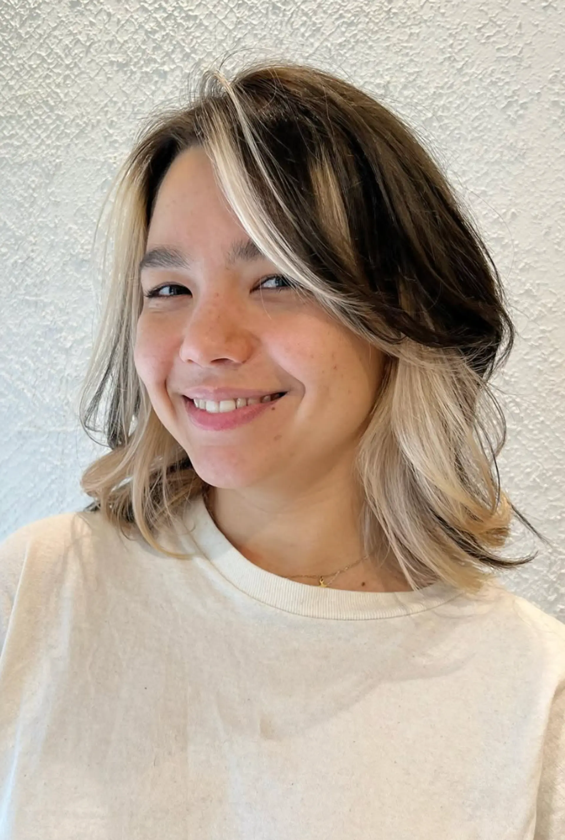 Medium-length wavy hairstyle with black as the base color and platinum blonde face-framing highlights. Features natural waves and soft layers for added dimension. 1