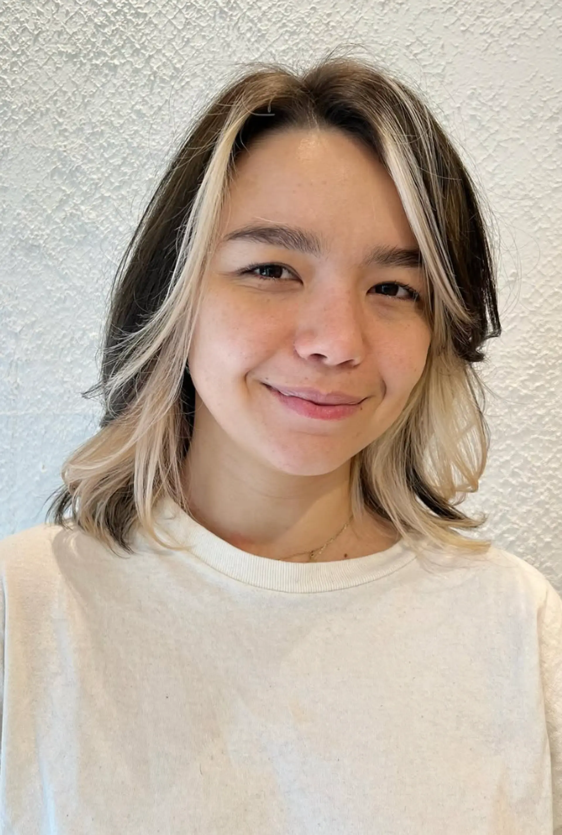 Medium-length wavy hairstyle with black as the base color and platinum blonde face-framing highlights. Features natural waves and soft layers for added dimension. 2