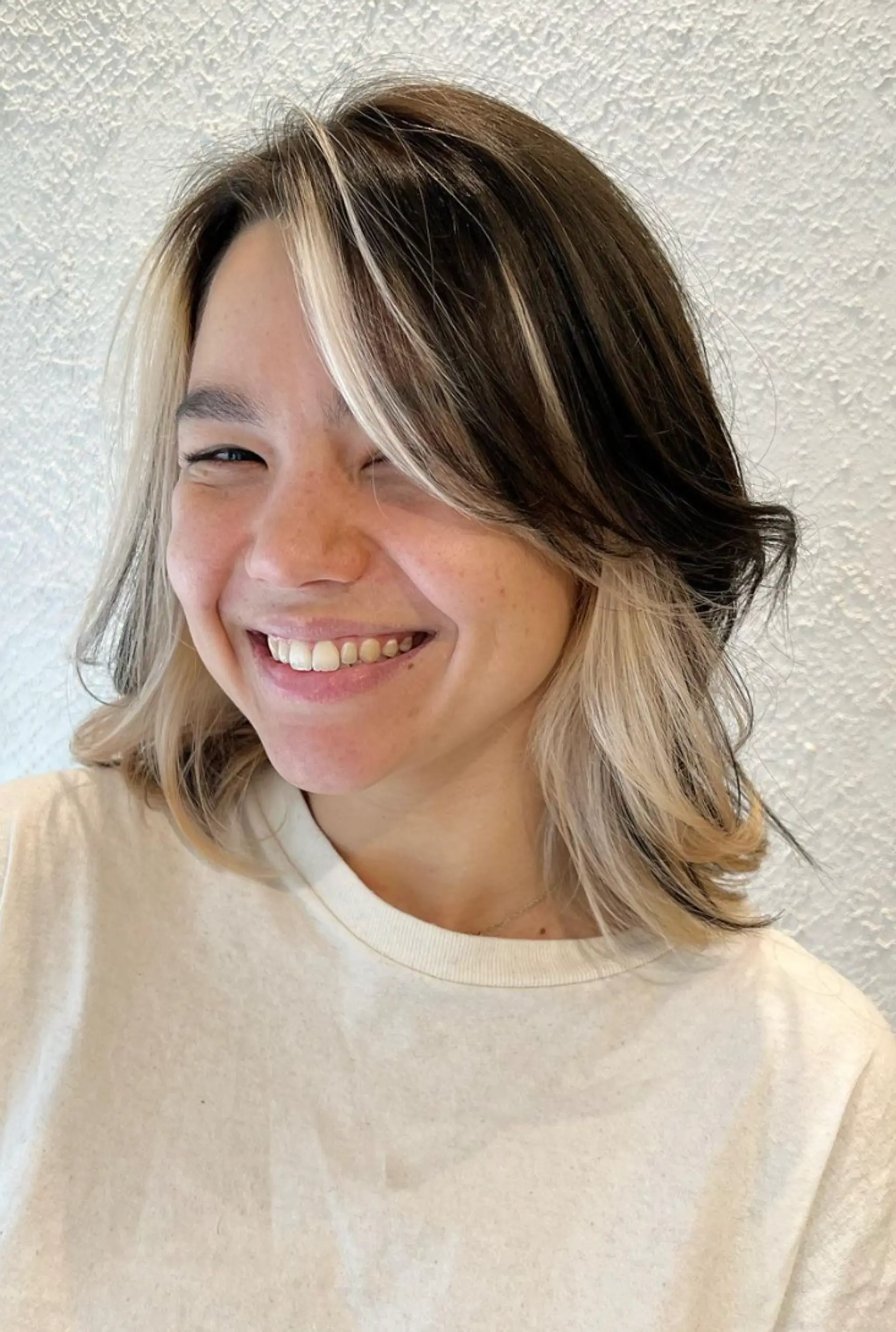 Medium-length wavy hairstyle with black as the base color and platinum blonde face-framing highlights. Features natural waves and soft layers for added dimension. 3