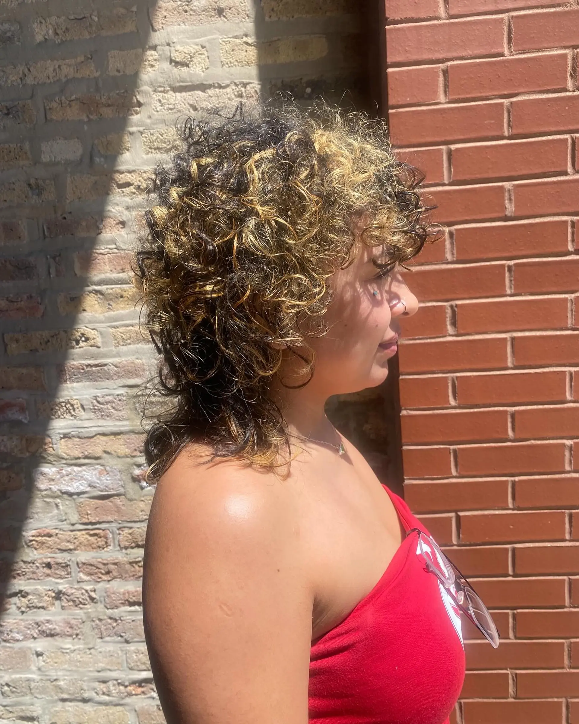 A shaggy, curly hairstyle with a trendy color contrast, with blonde highlights on black hair. 1