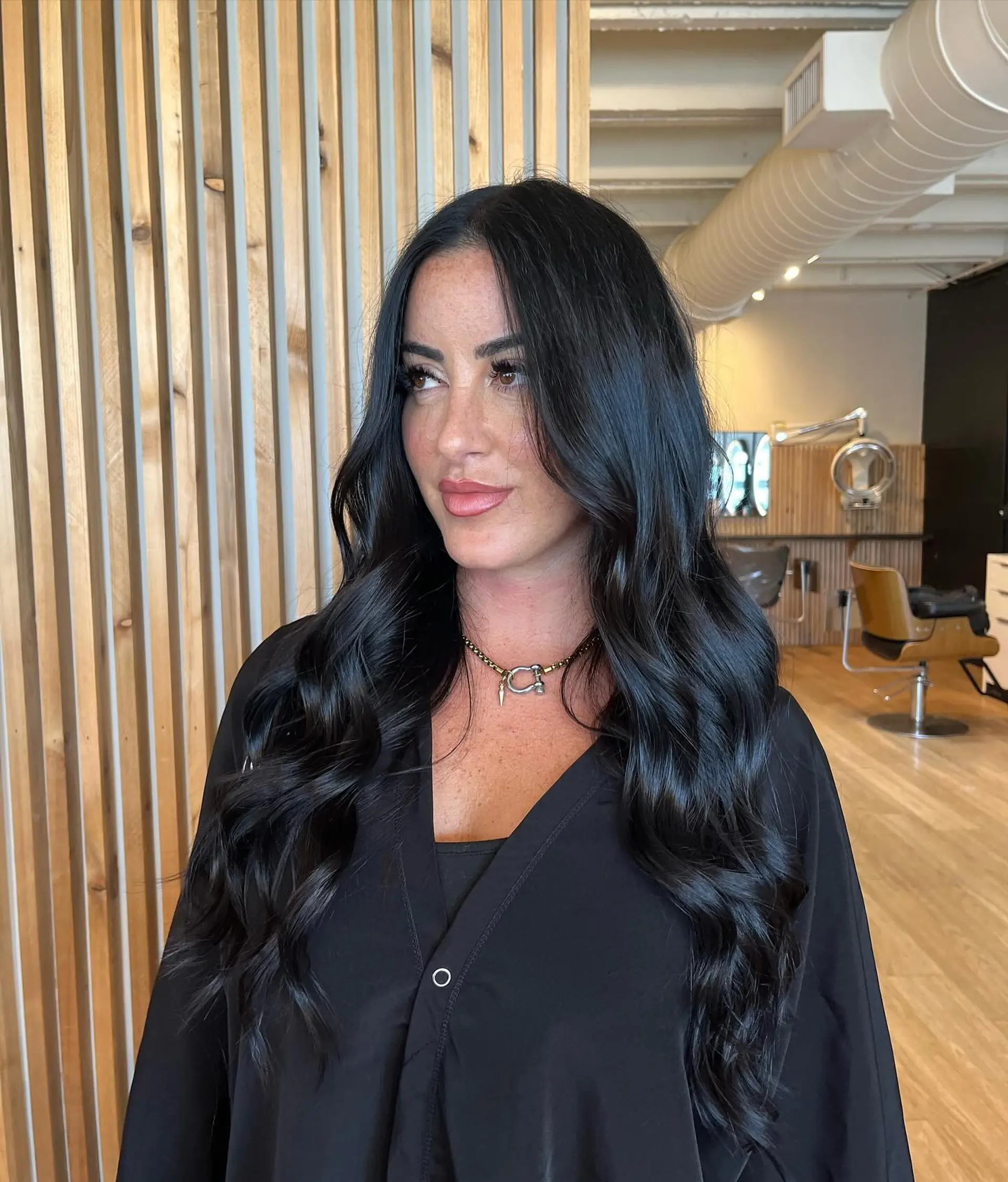 Long, midnight black hair styled with soft, voluminous waves and a high-shine finish. 1