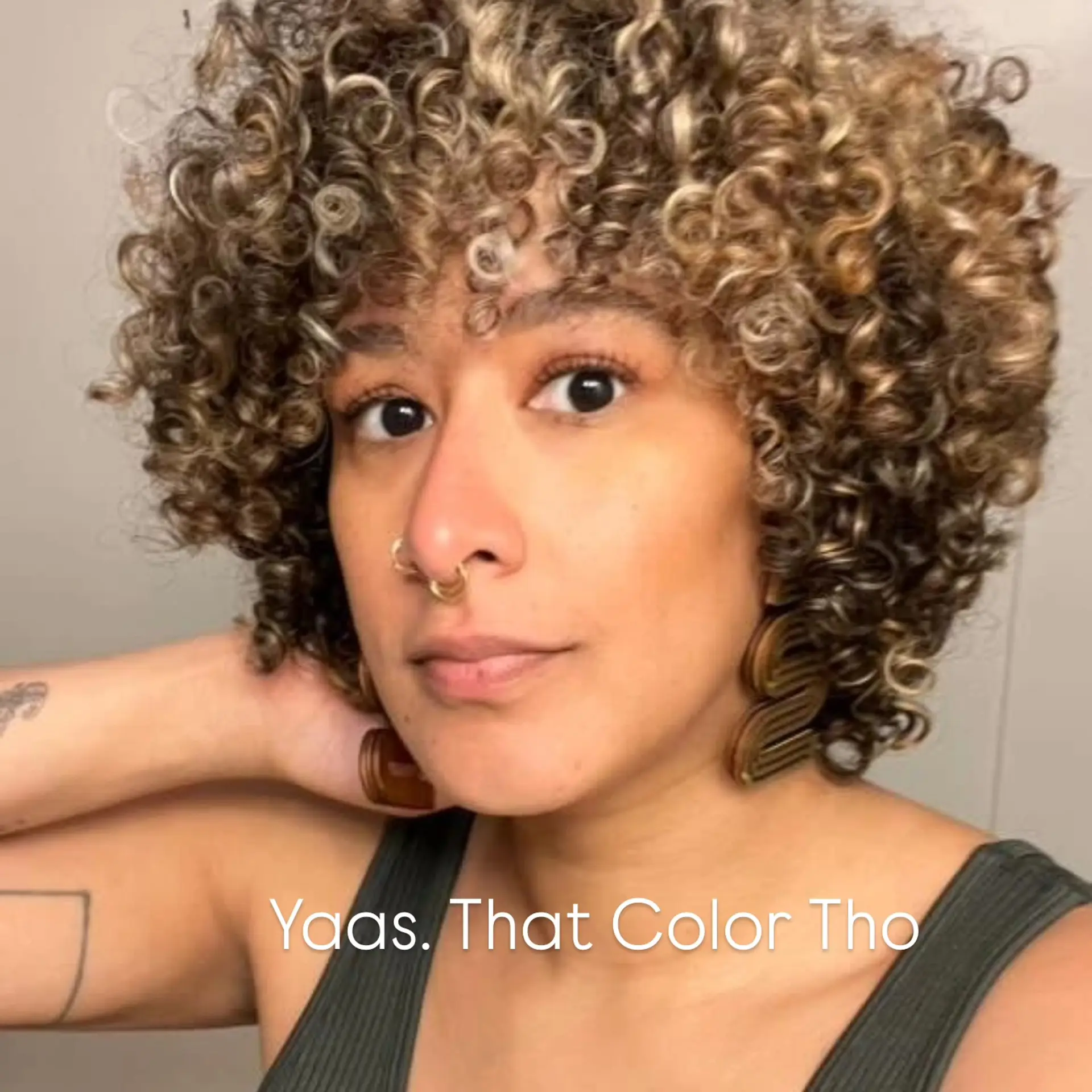 A rounded curly cut featuring tight, defined spiral curls and front fringe, accented with radiant golden blonde balayage highlights. 1