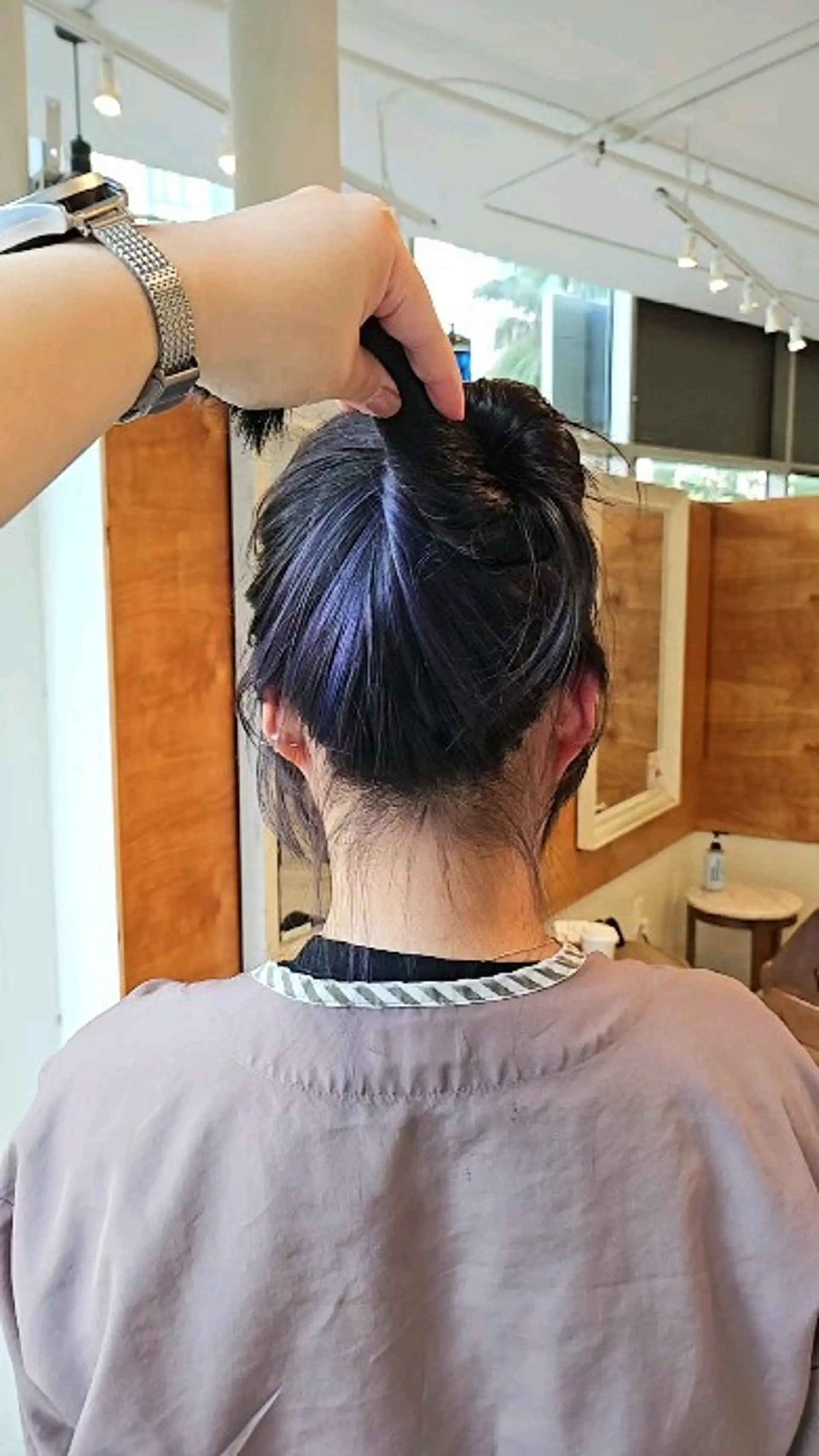 A peekaboo hair coloring style showcasing hidden ash purple highlights beneath dark hair. 1