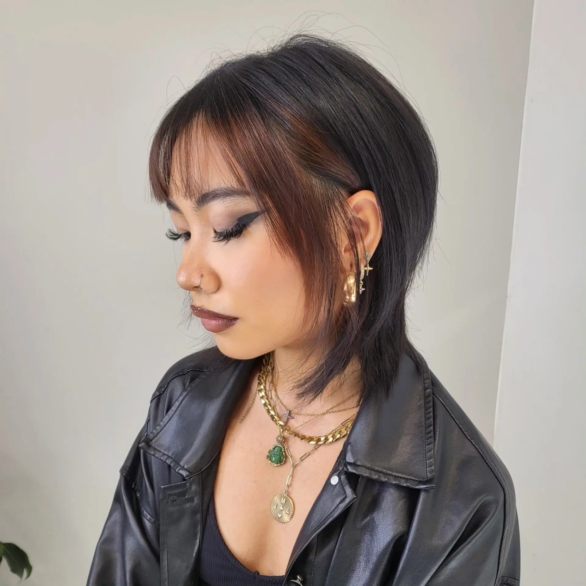 A textured short wolf cut featuring wispy fringe bangs and warm brown face-framing highlights. 1