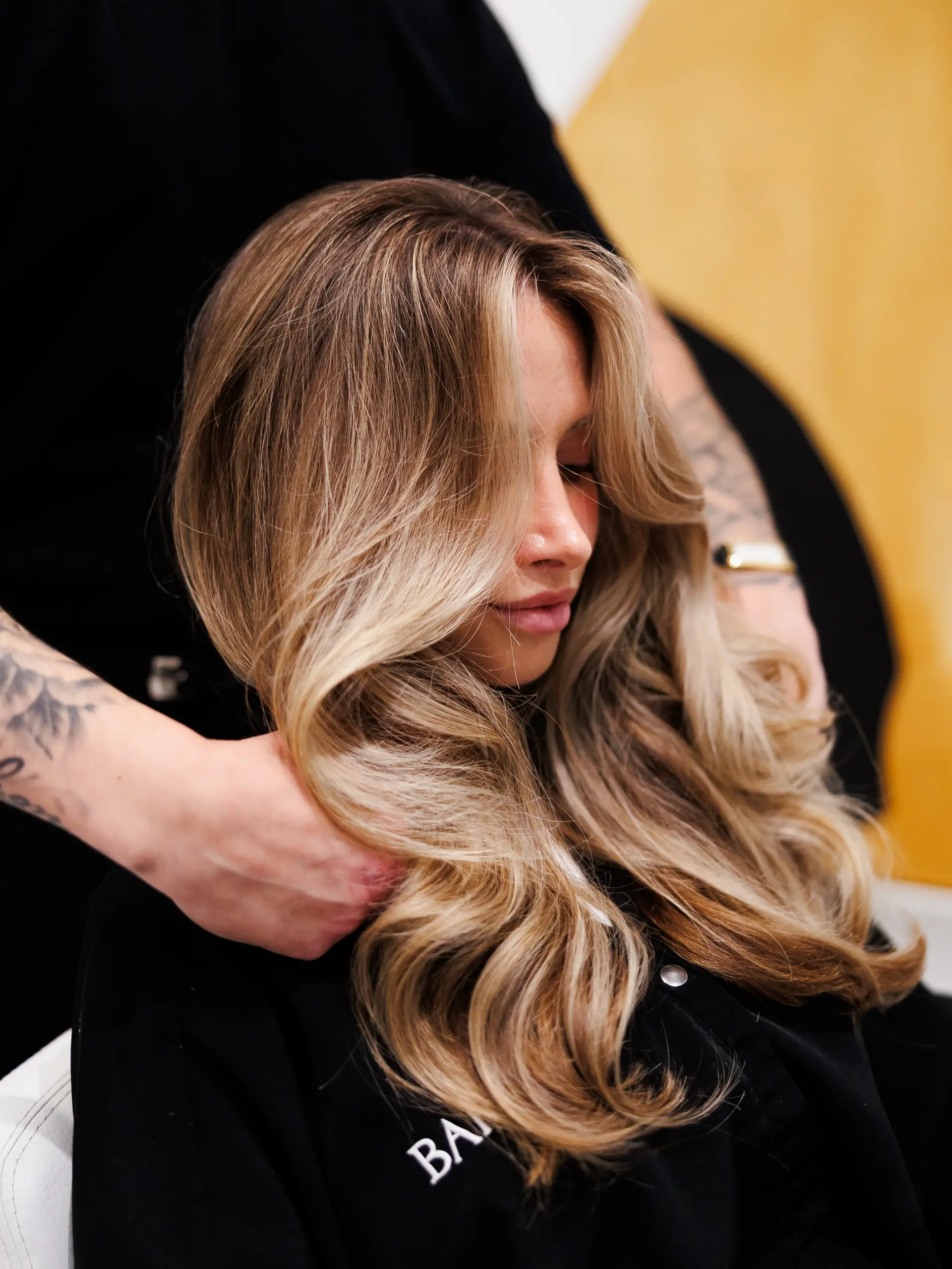 Voluminous lived-in blonde blowout featuring soft, cascading waves and curtain bangs framing the face. 1