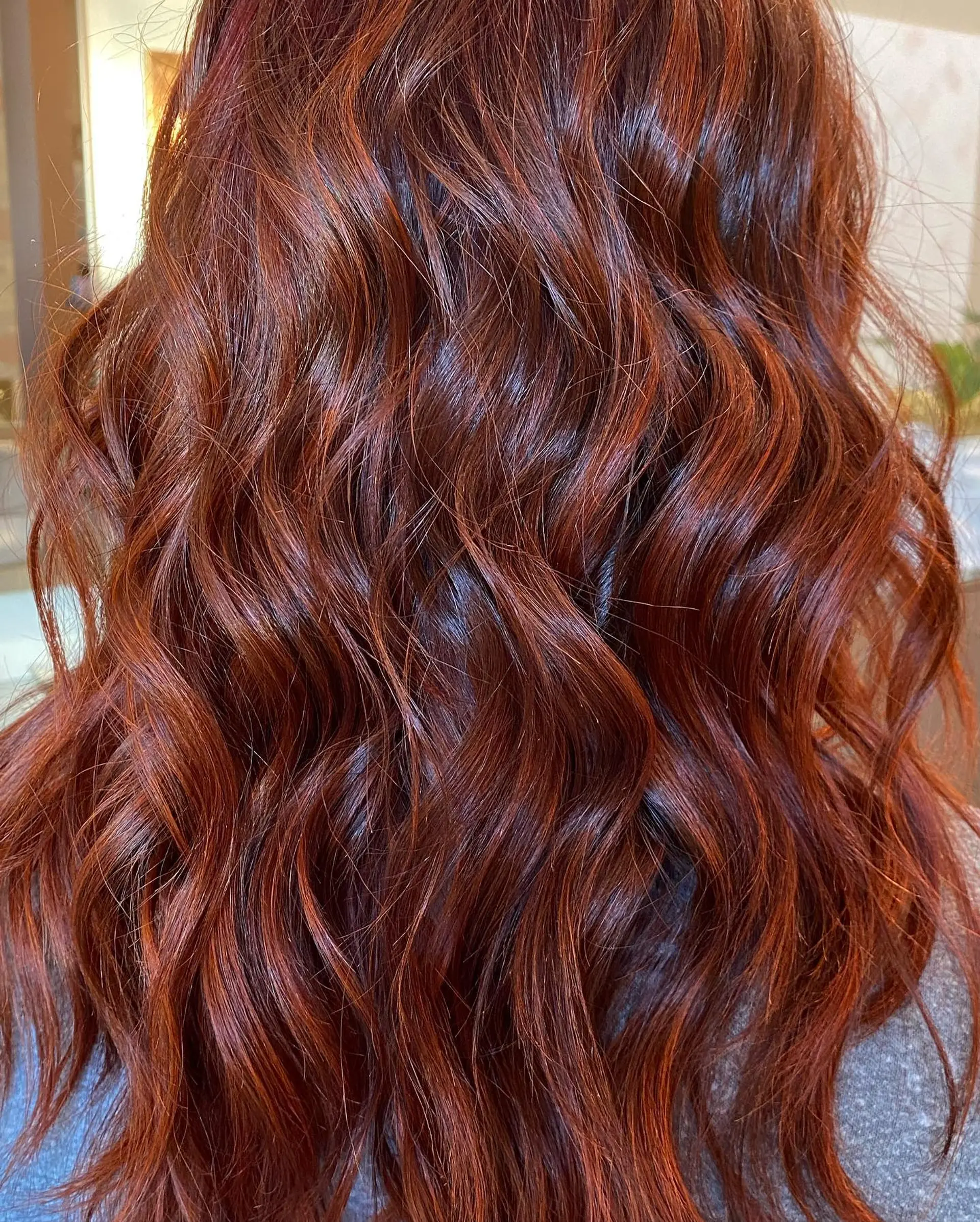 Rich, multi-dimensional auburn red hair styled into loose, glossy textured waves. 1