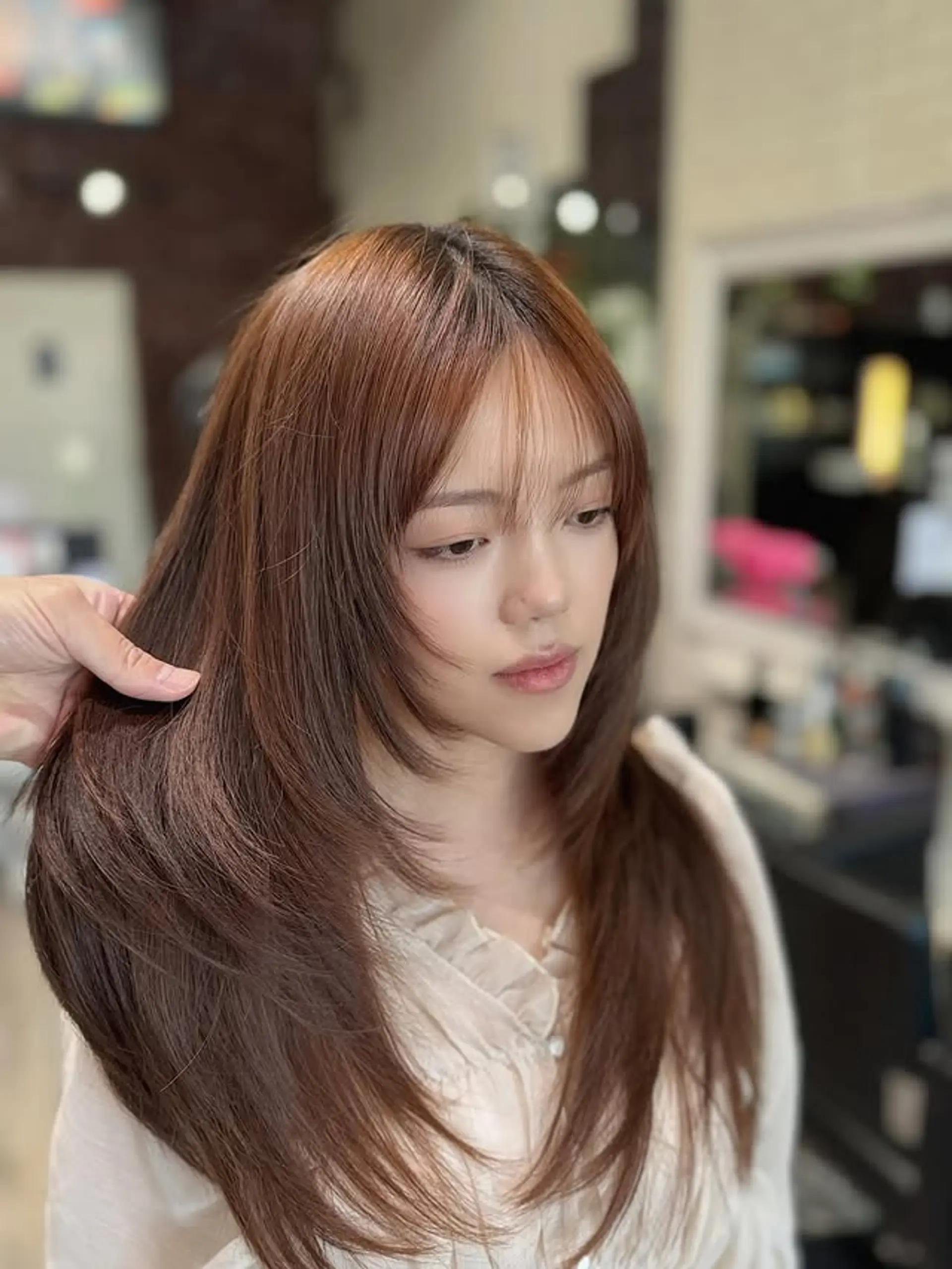 This style showcases long, flowing layers that frame the face beautifully, adding softness and dimension. It includes delicate wispy, see-through bangs that gently sweep across the forehead, enhancing a youthful and elegant aesthetic. 1