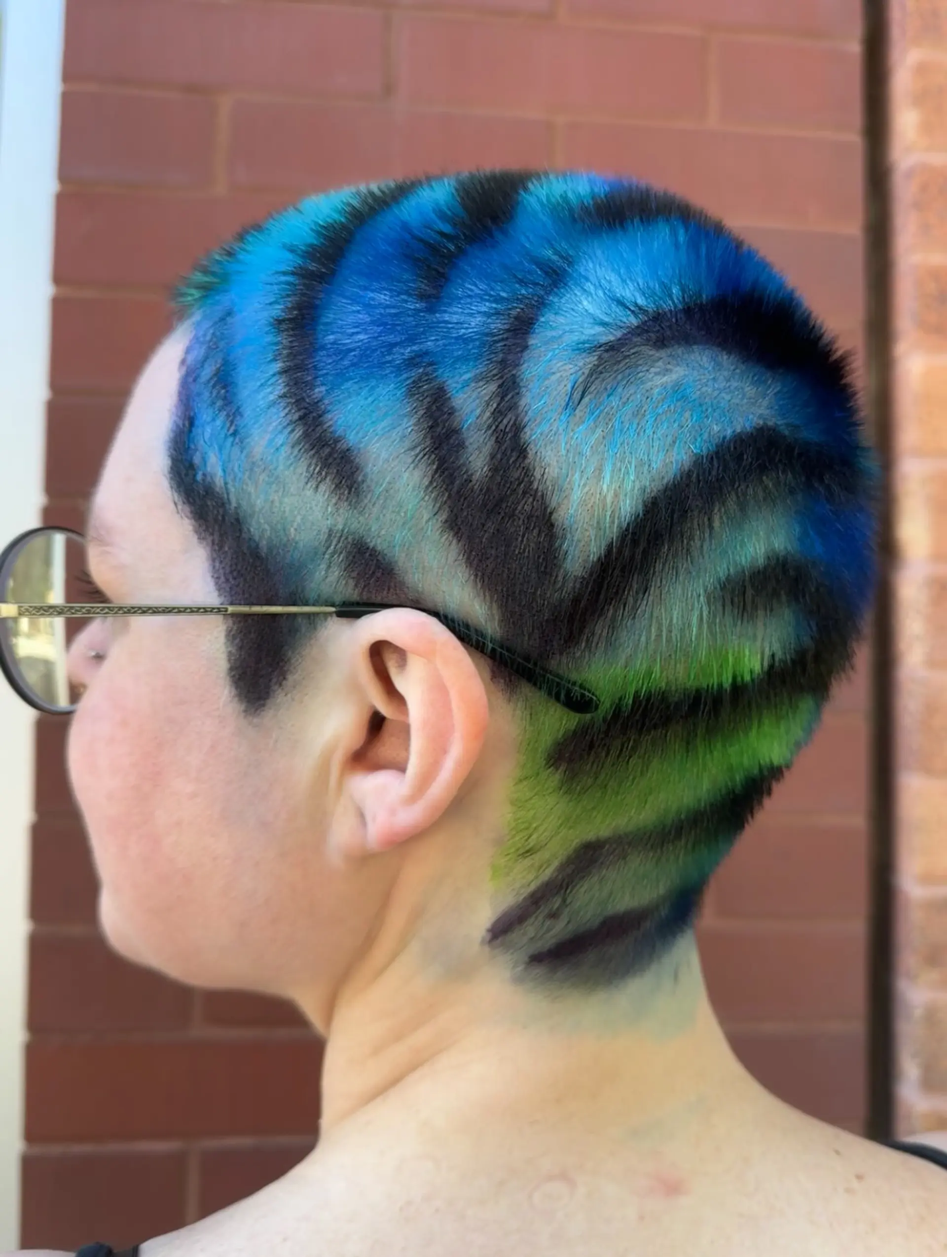 A close buzz cut featuring a vivid blue-to-green gradient painted with bold black tiger stripes. 1