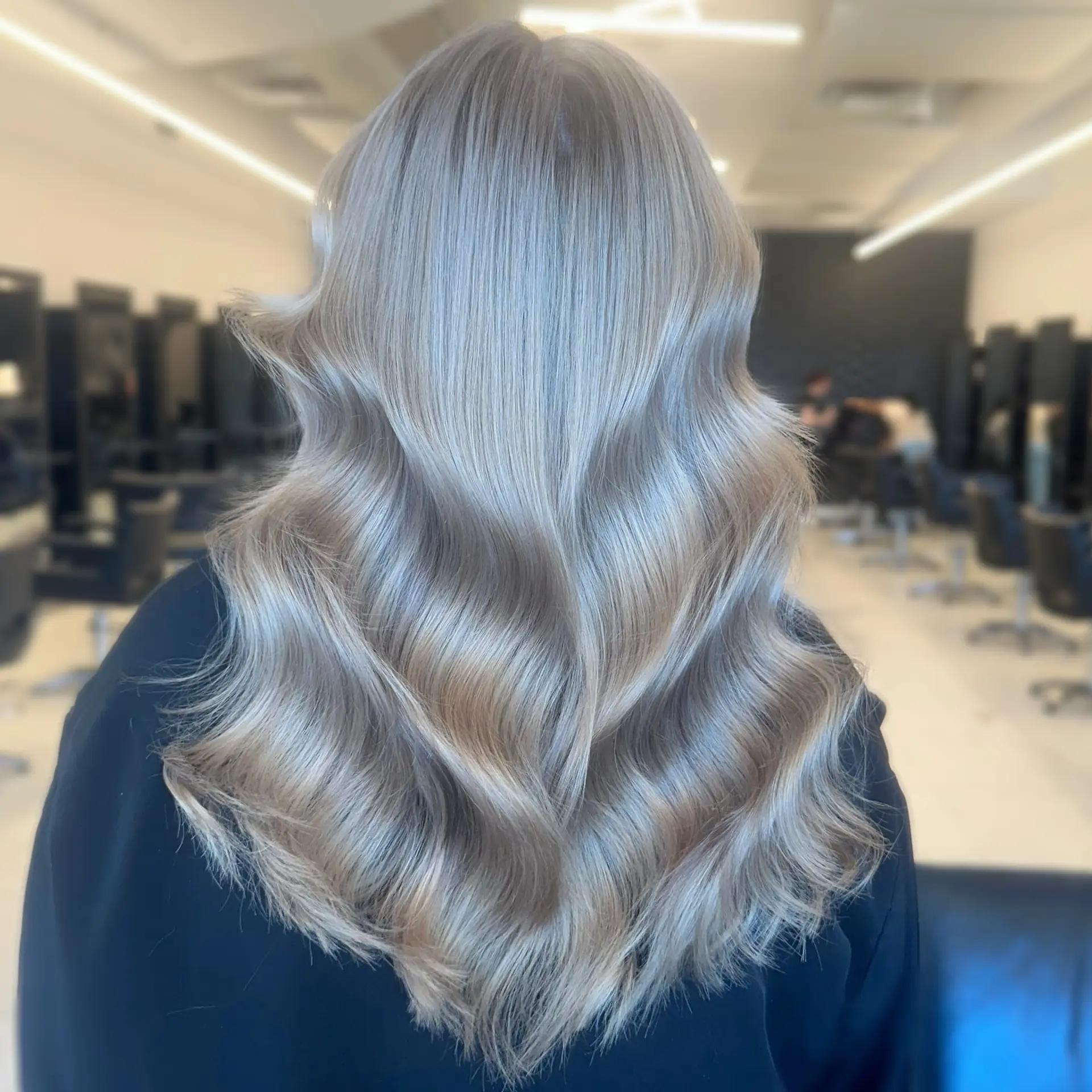 Long, luminous ash blonde hair with a mirror-like shine styled in soft, cascading waves. 1