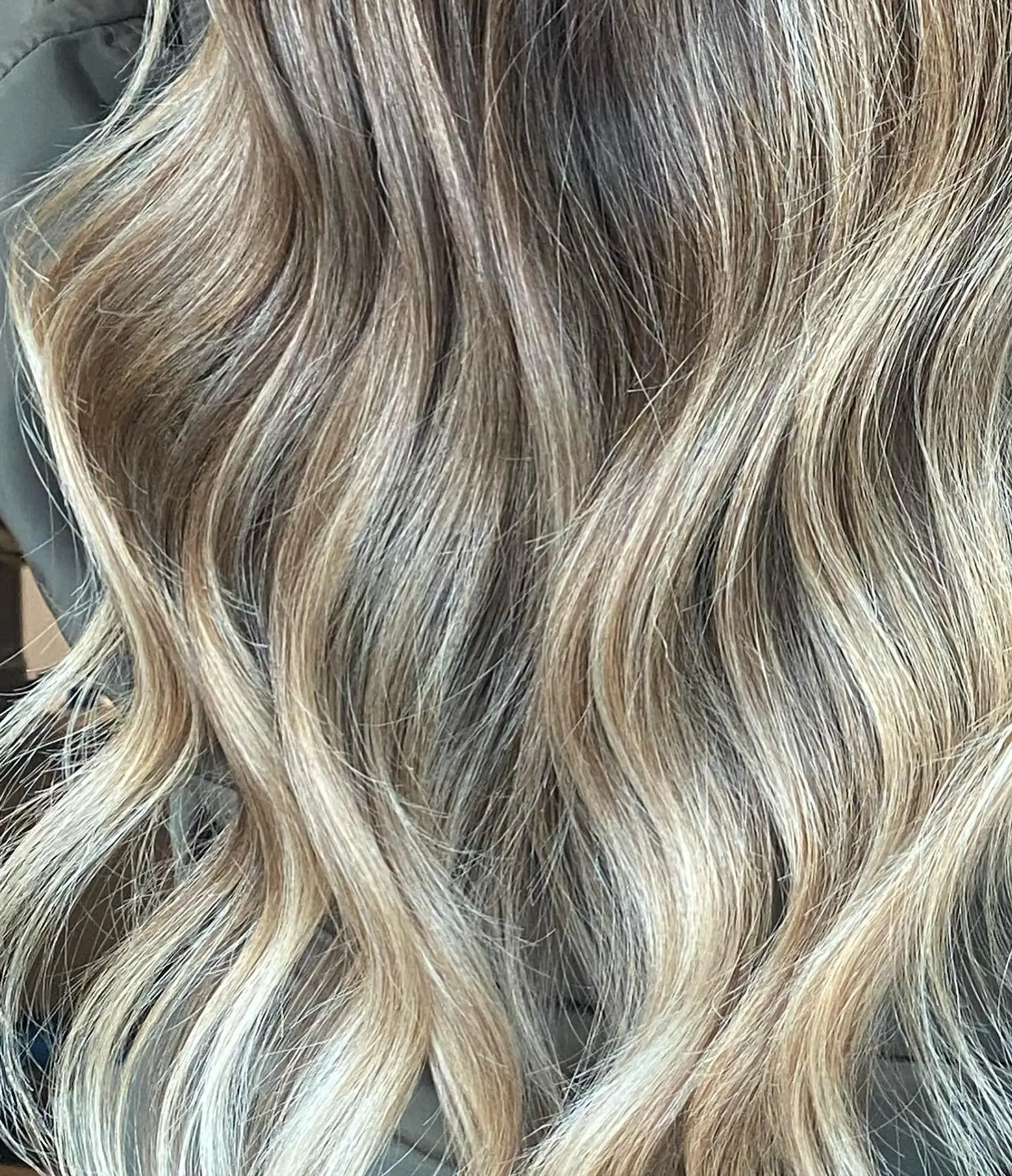 Long wavy hair with cool-toned dimensional blonde highlights and soft textured waves. 1