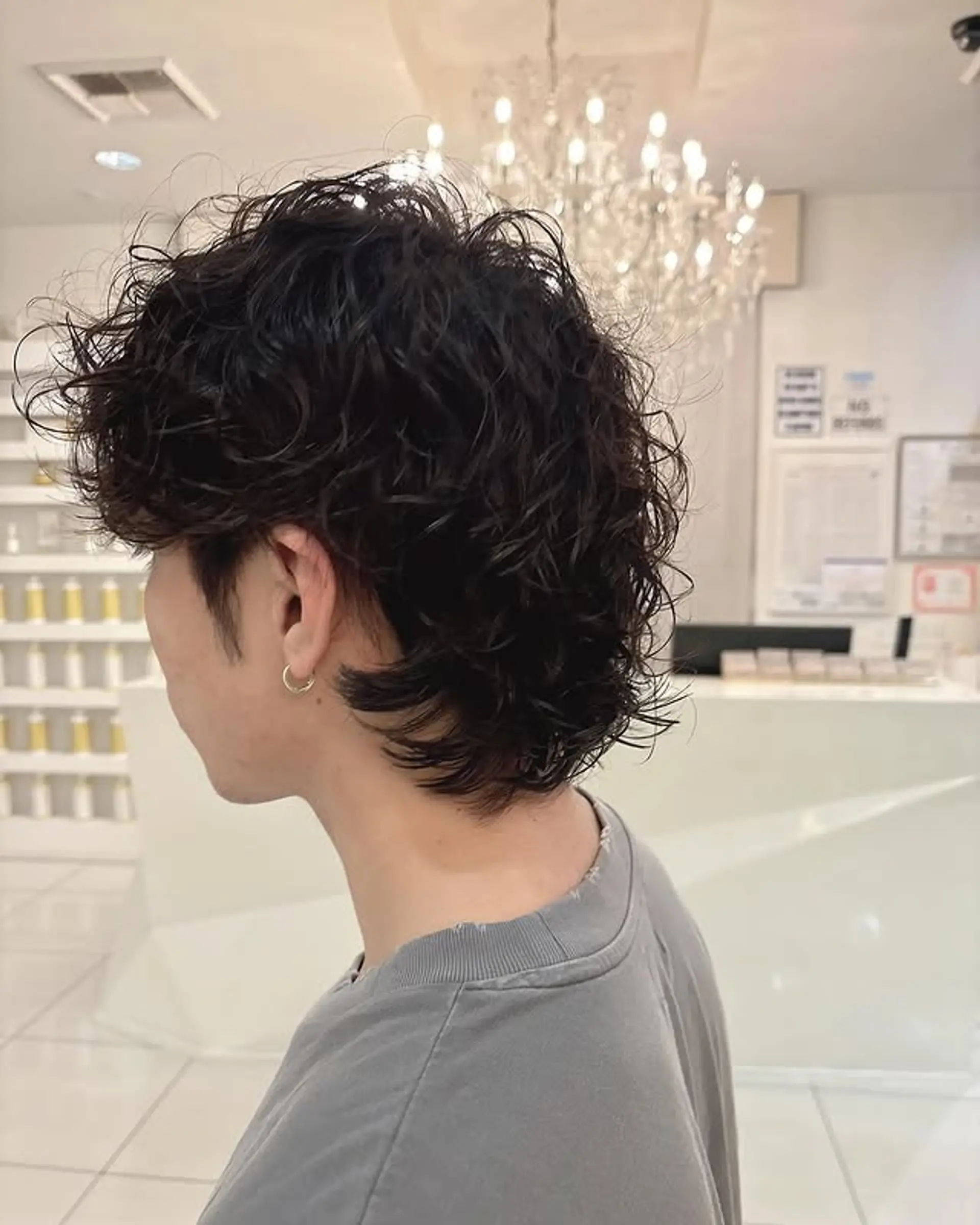 The hairstyle is a perm with a bro flow and gives a textured, curly look. 1