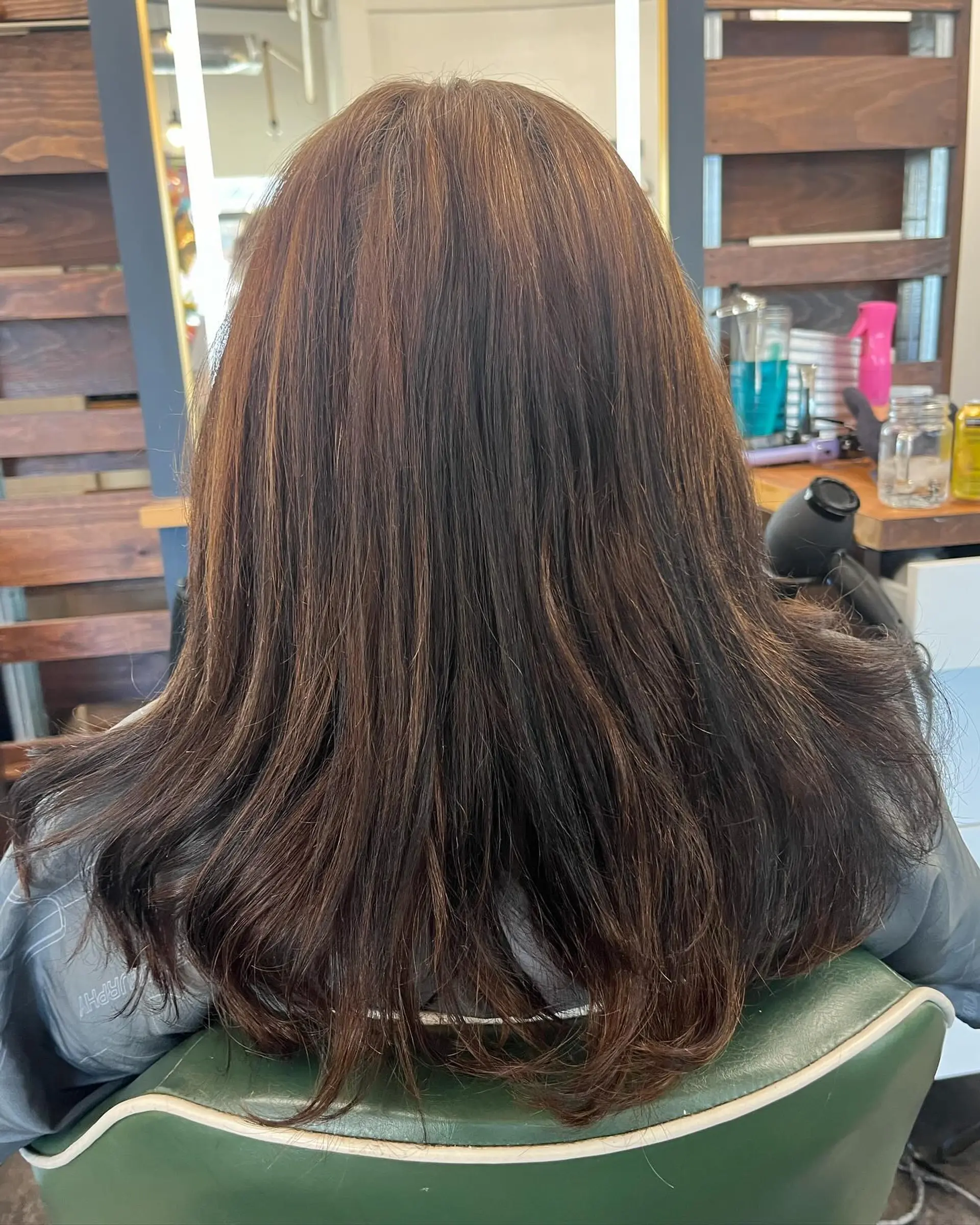 Medium-length dimensional brunette hair styled smooth with a soft natural flip at the ends. 1