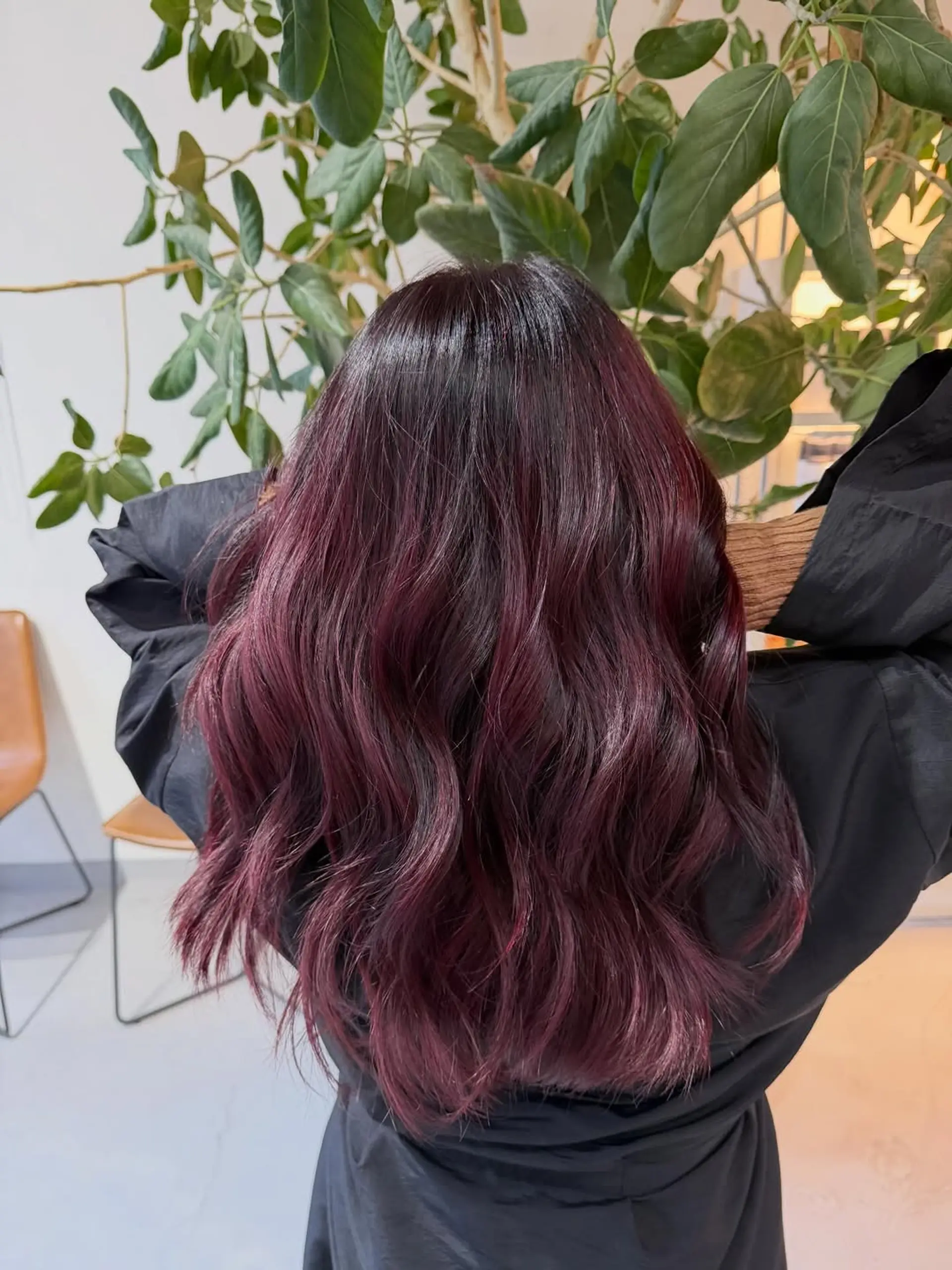 Long hair styled in soft, loose waves with deep burgundy and plum dimensional coloring. 1