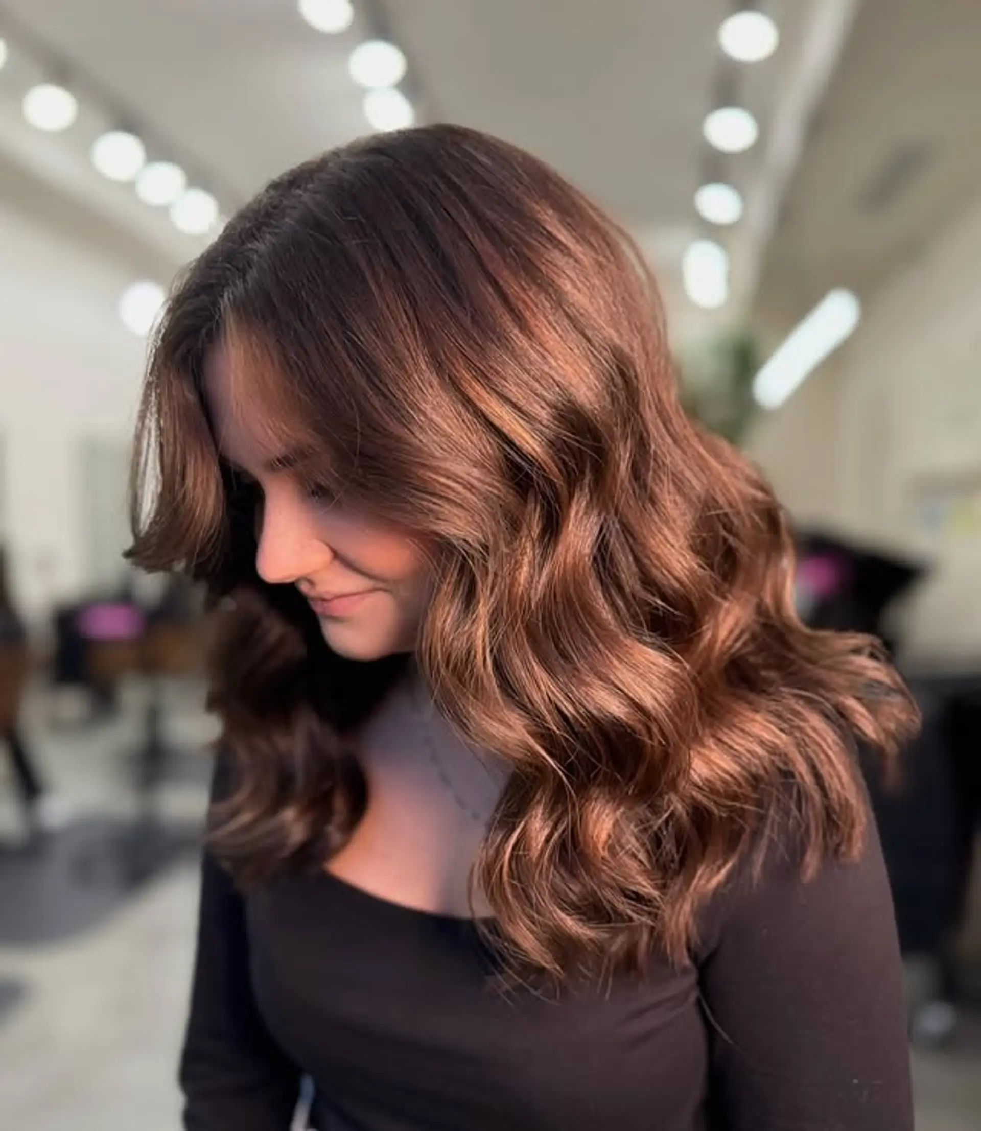 Wavy medium-length hair with copper bronde color and curtain bangs. 1