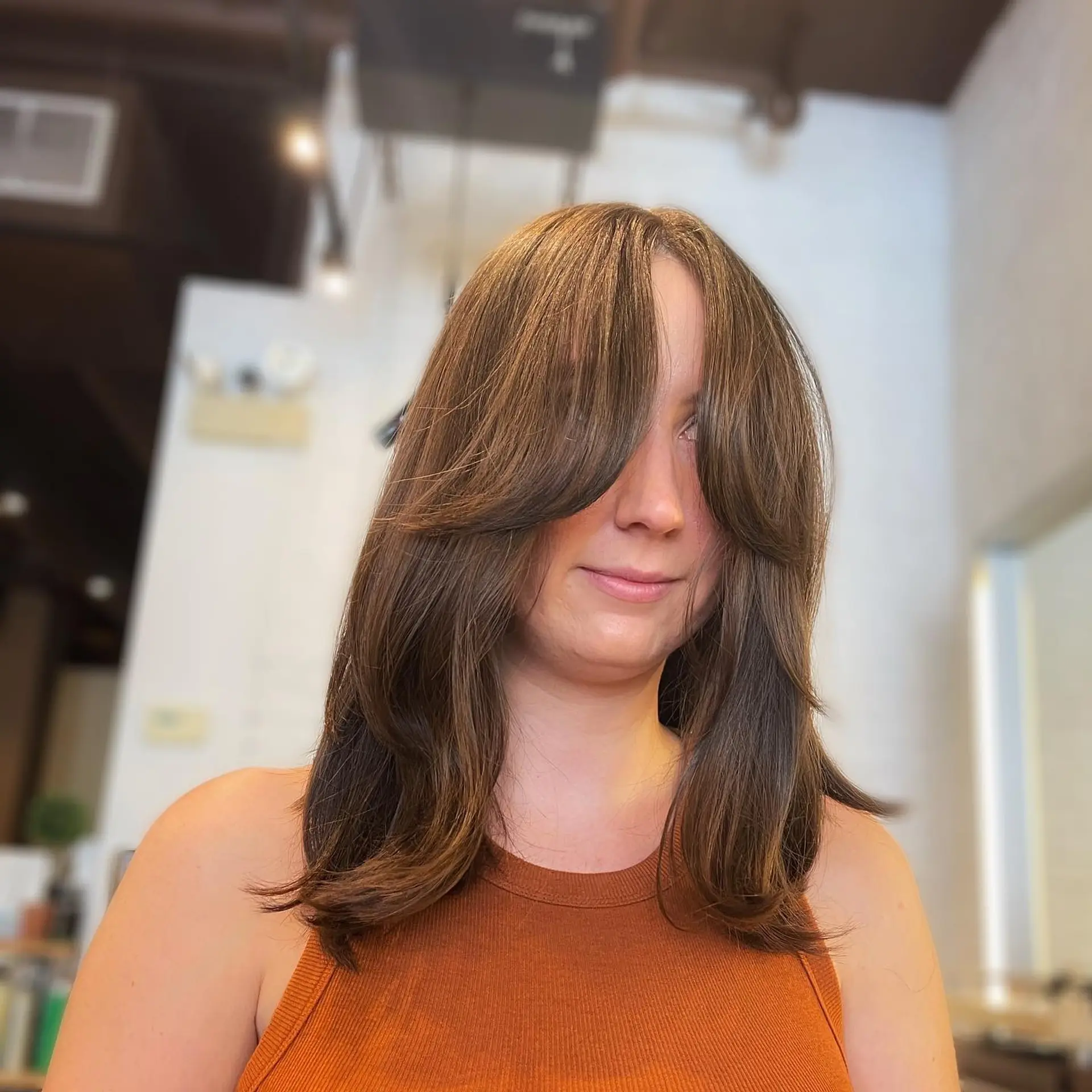 Curtain bangs and face-framing layers create a modern and trendy look. 1