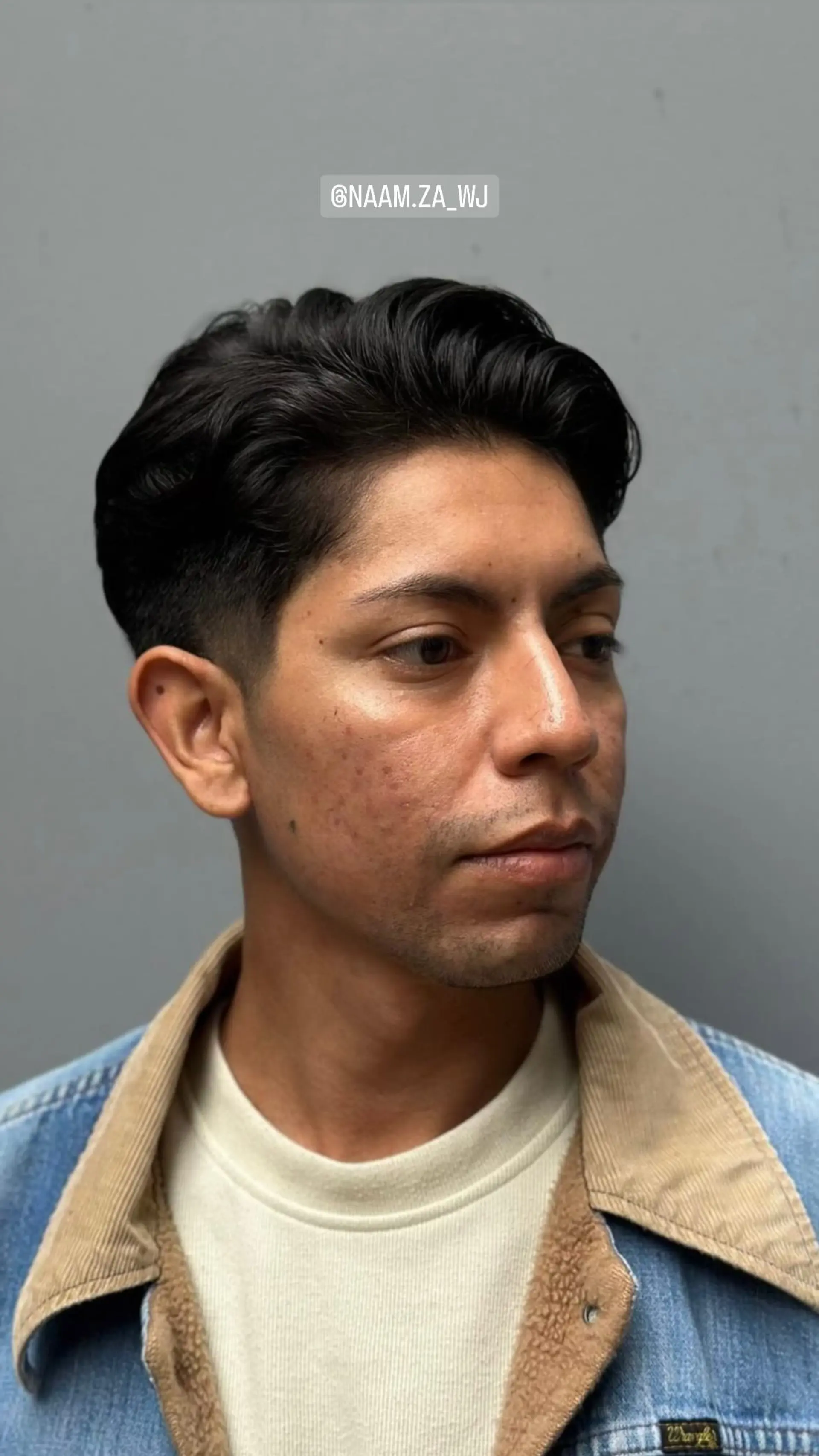 A classic men's haircut featuring tapered sides and a textured, wavy top. 1