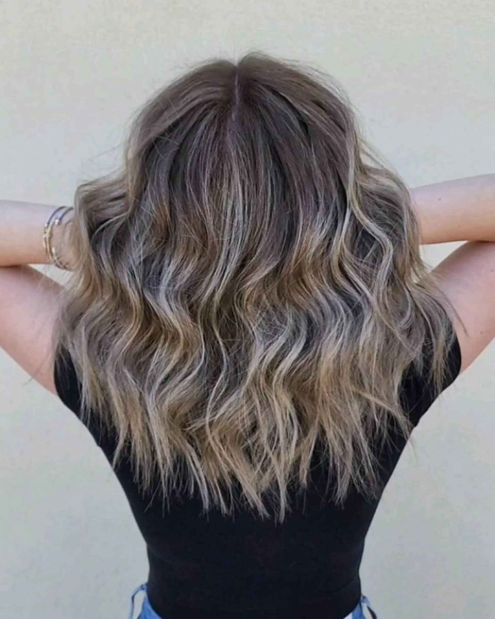 Medium-length textured waves featuring a cool-toned ash blonde foilayage seamlessly blended with natural brunette roots. 1