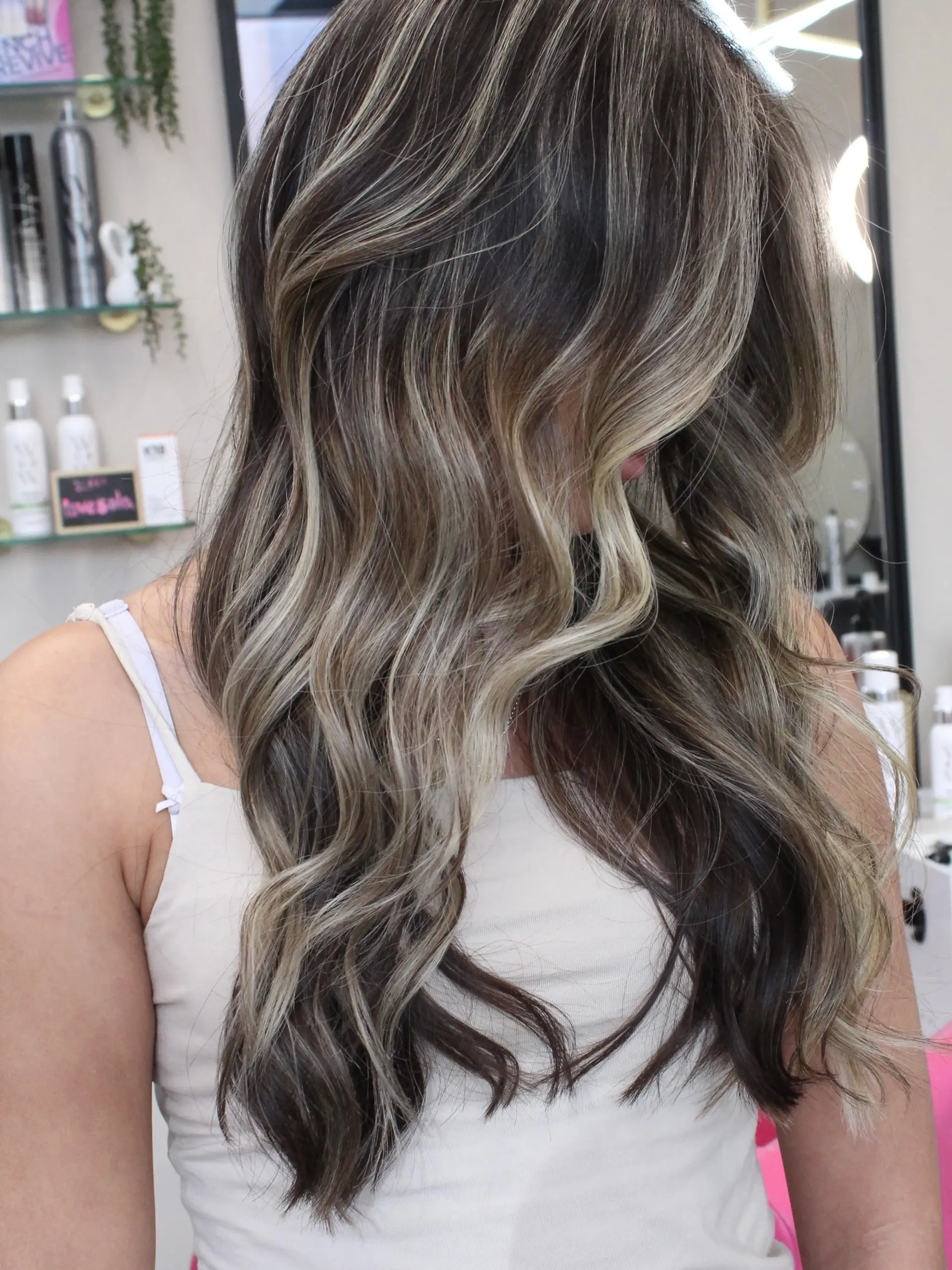 Long dark brown hair layered with cool ash blonde highlights and finished in soft, loose waves. 1