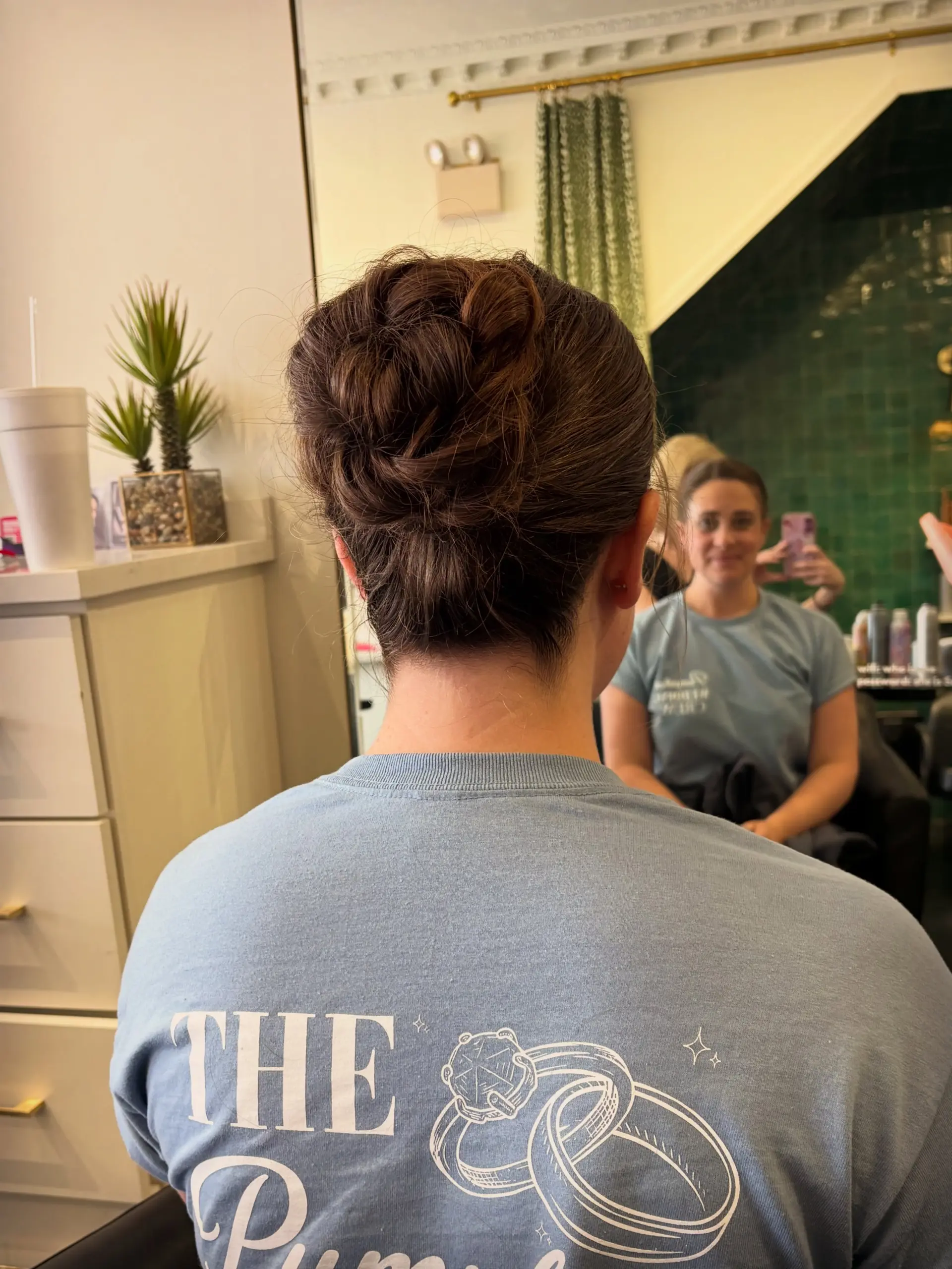 A sleek, elegant low-to-mid updo featuring textured twists and loops pinned neatly at the back. 1