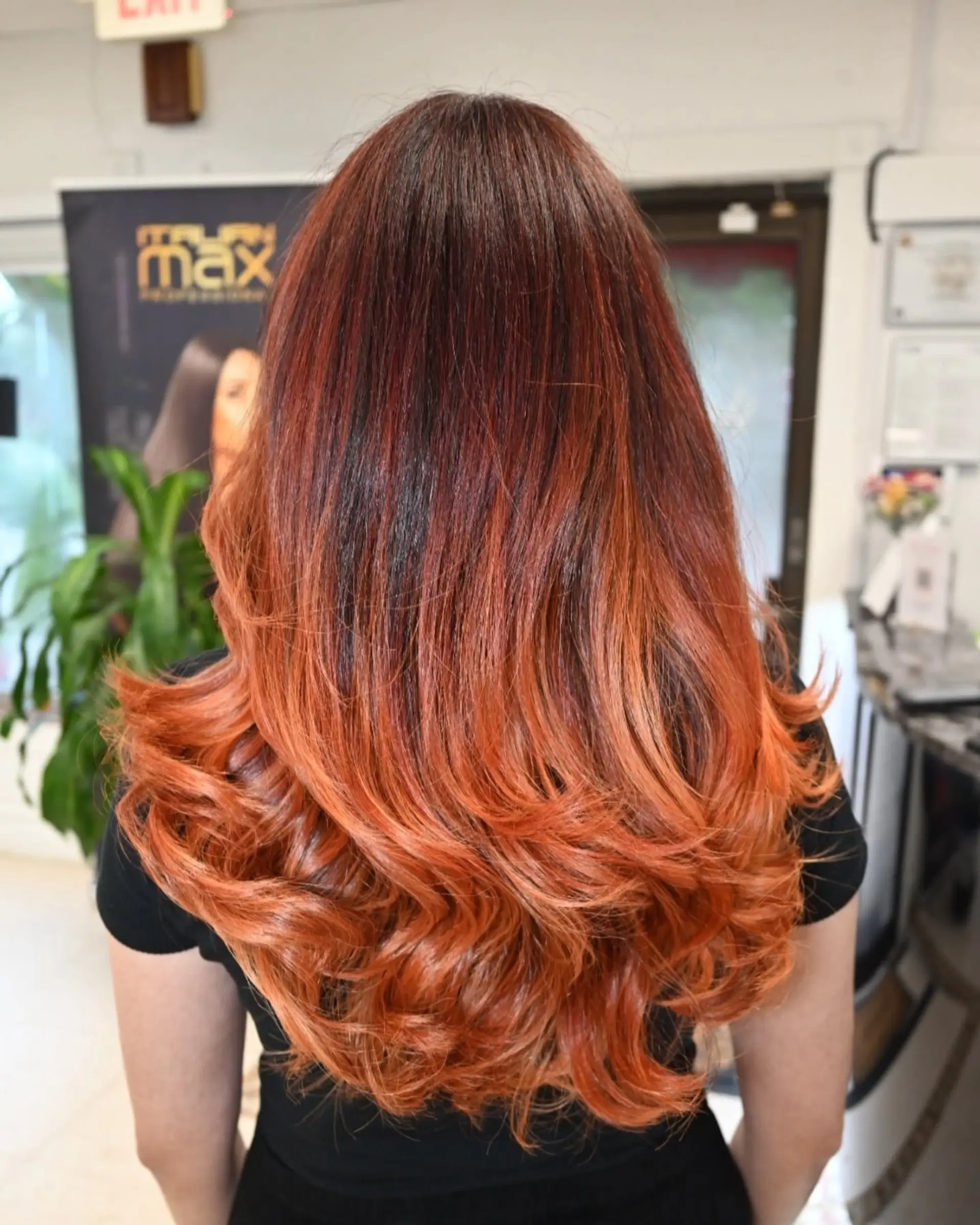 Long dark auburn hair seamlessly blending into bright copper balayage highlights, styled with bouncy, voluminous curls at the ends. 1