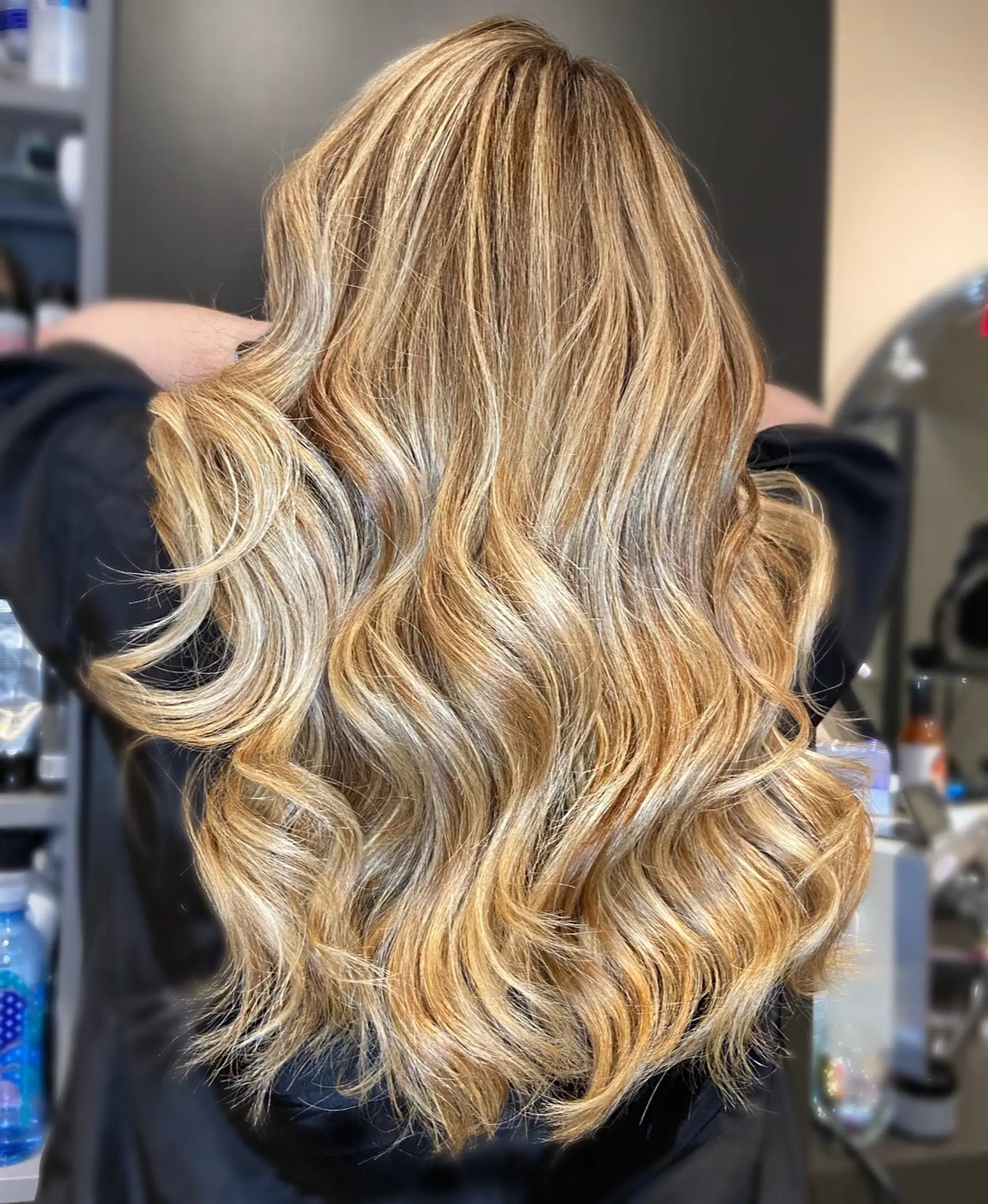 Long honey blonde hair featuring multidimensional highlights and soft, voluminous waves. 1