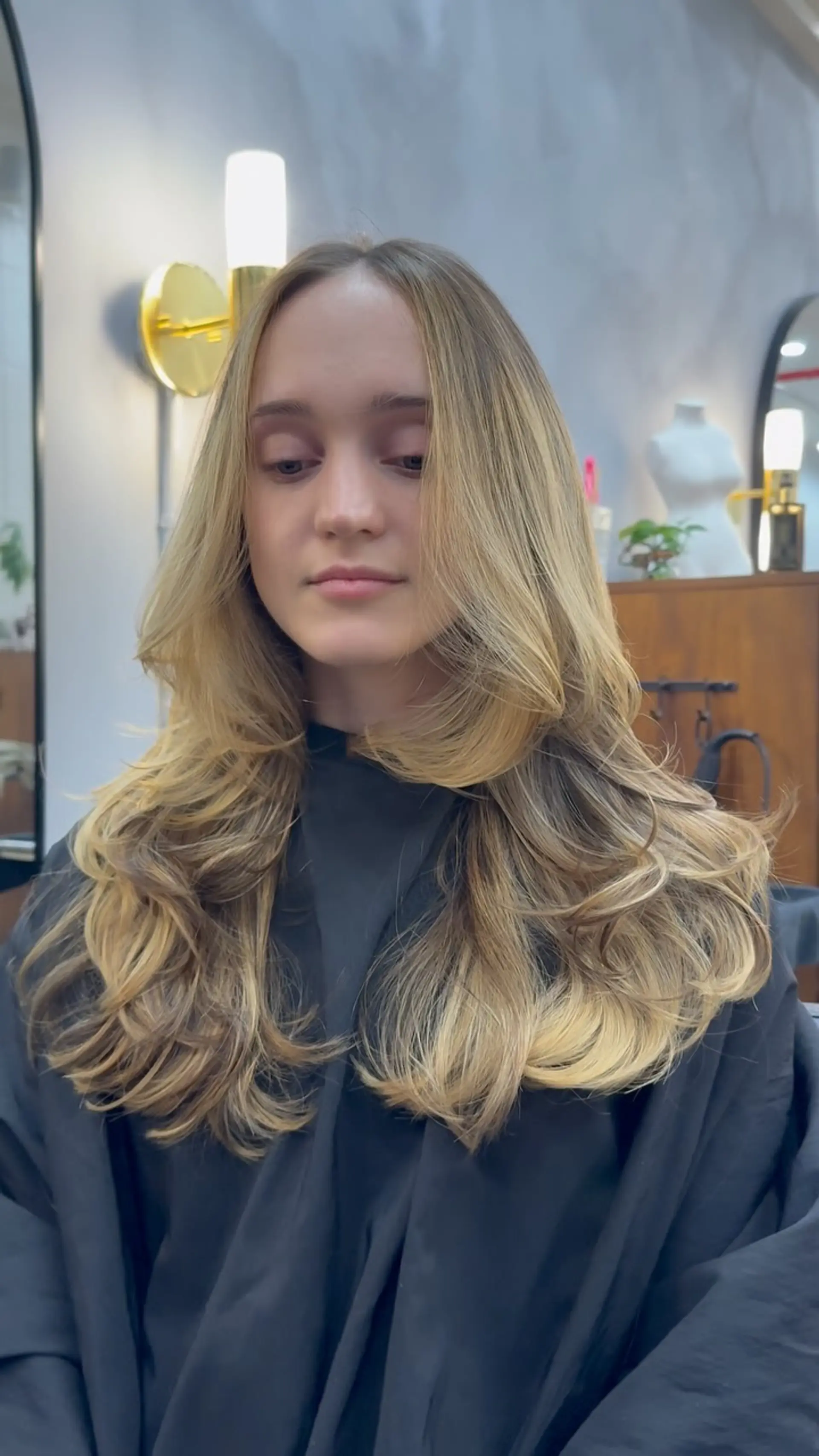 Long warm blonde hair styled with prominent face-framing layers and voluminous curled-under ends. 1