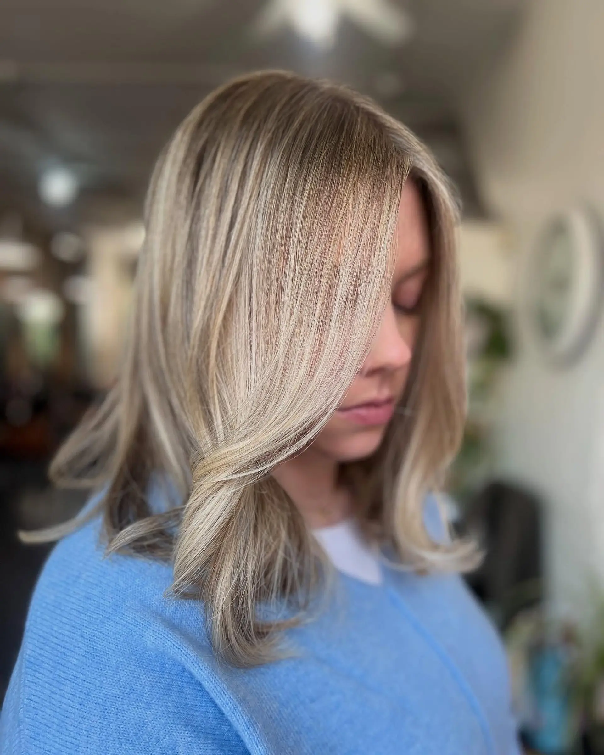 Medium-length dimensional blonde hair styled smooth with a soft curved front fringe and flipped ends. 1