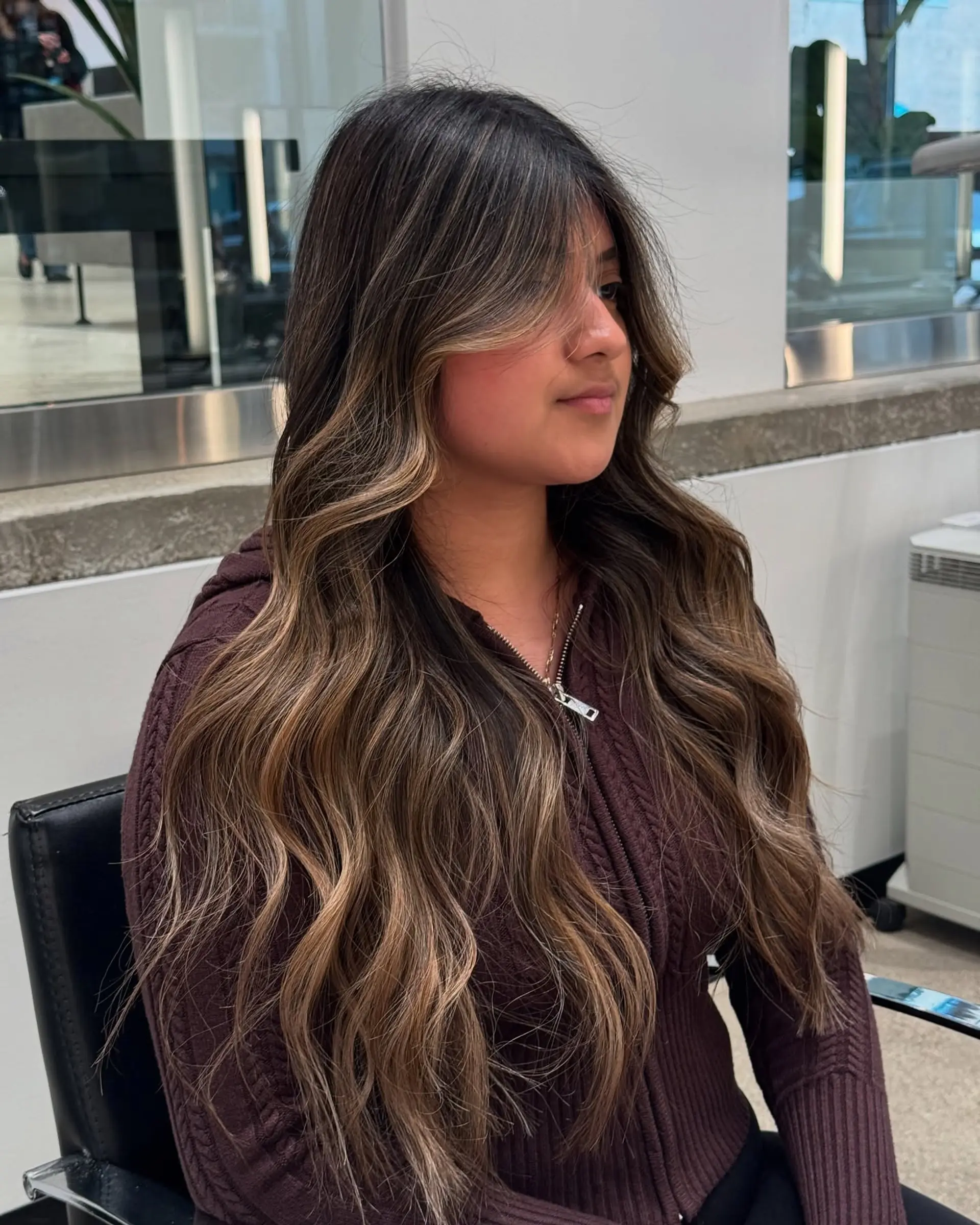 A long, wavy hairstyle with a beautiful balayage and face-framing curtain bangs. 1