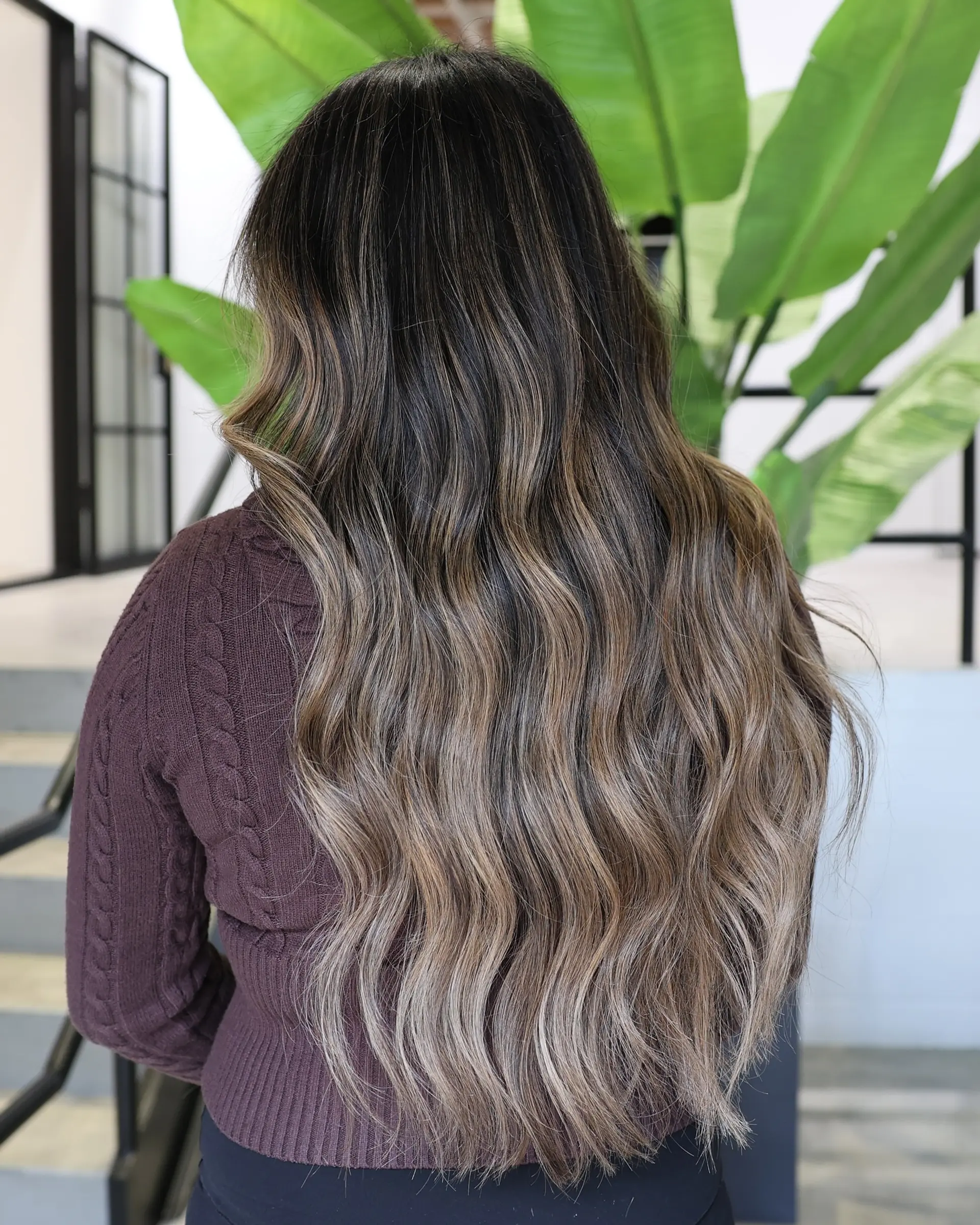 A long, wavy hairstyle with a beautiful balayage and face-framing curtain bangs. 2