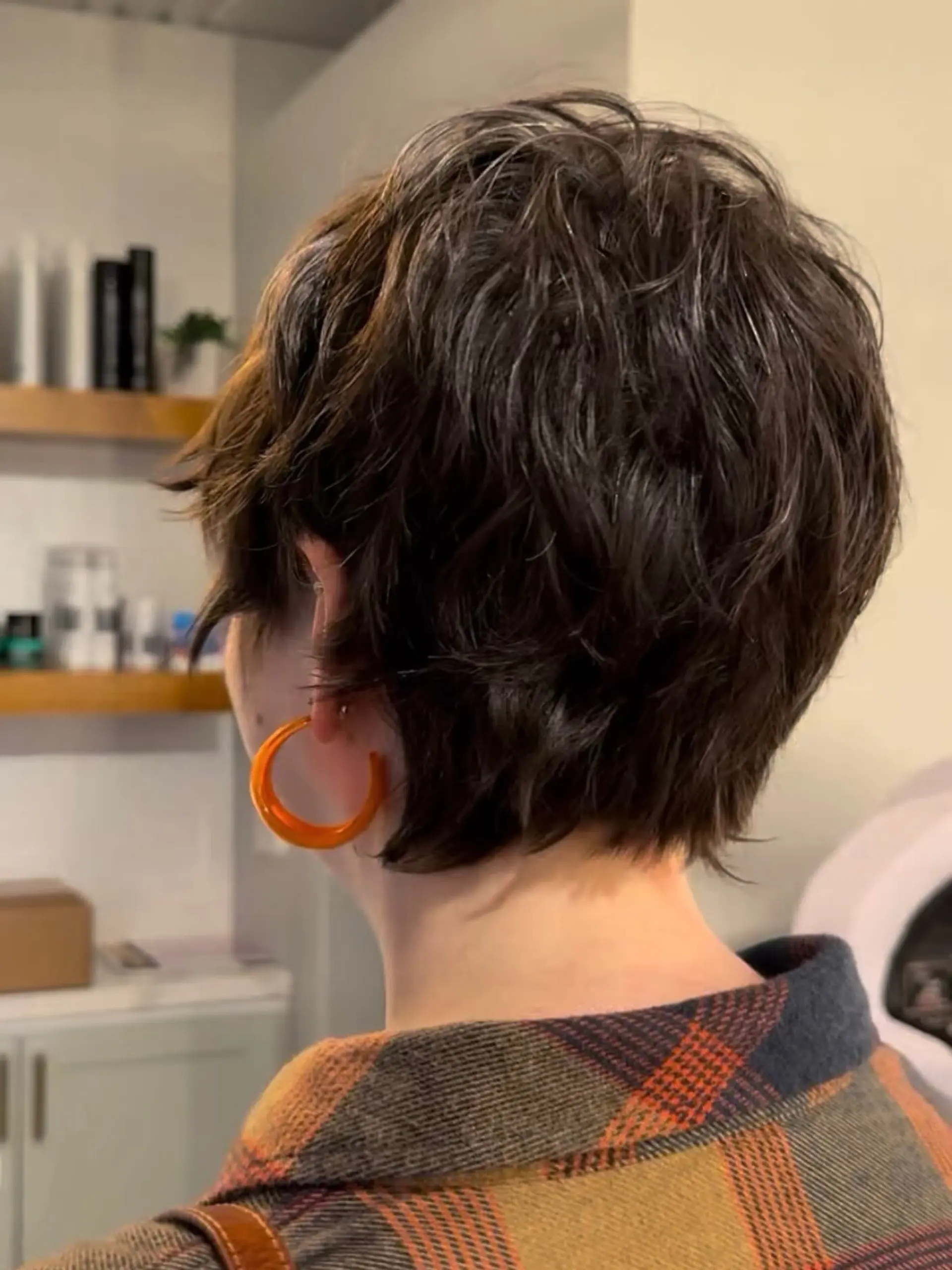 A textured short pixie haircut styled with soft internal layers, natural wavy movement, and a feathery perimeter. 1