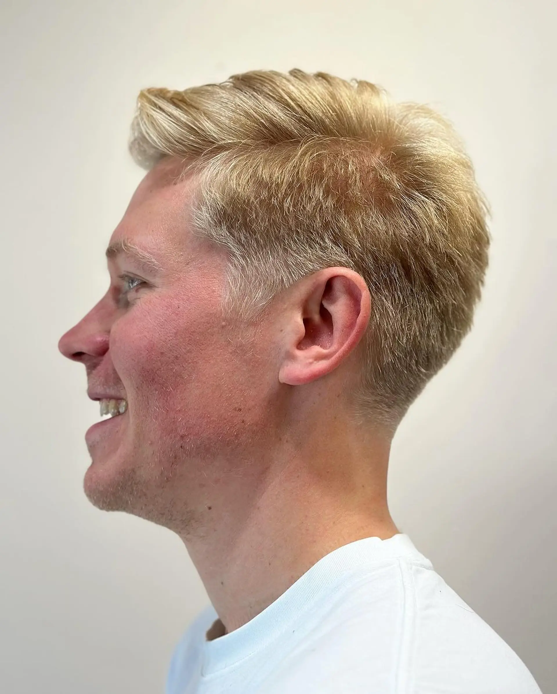 A sleek and short blonde hairstyle with tapered sides and a textured top, featuring a subtle side part. 1