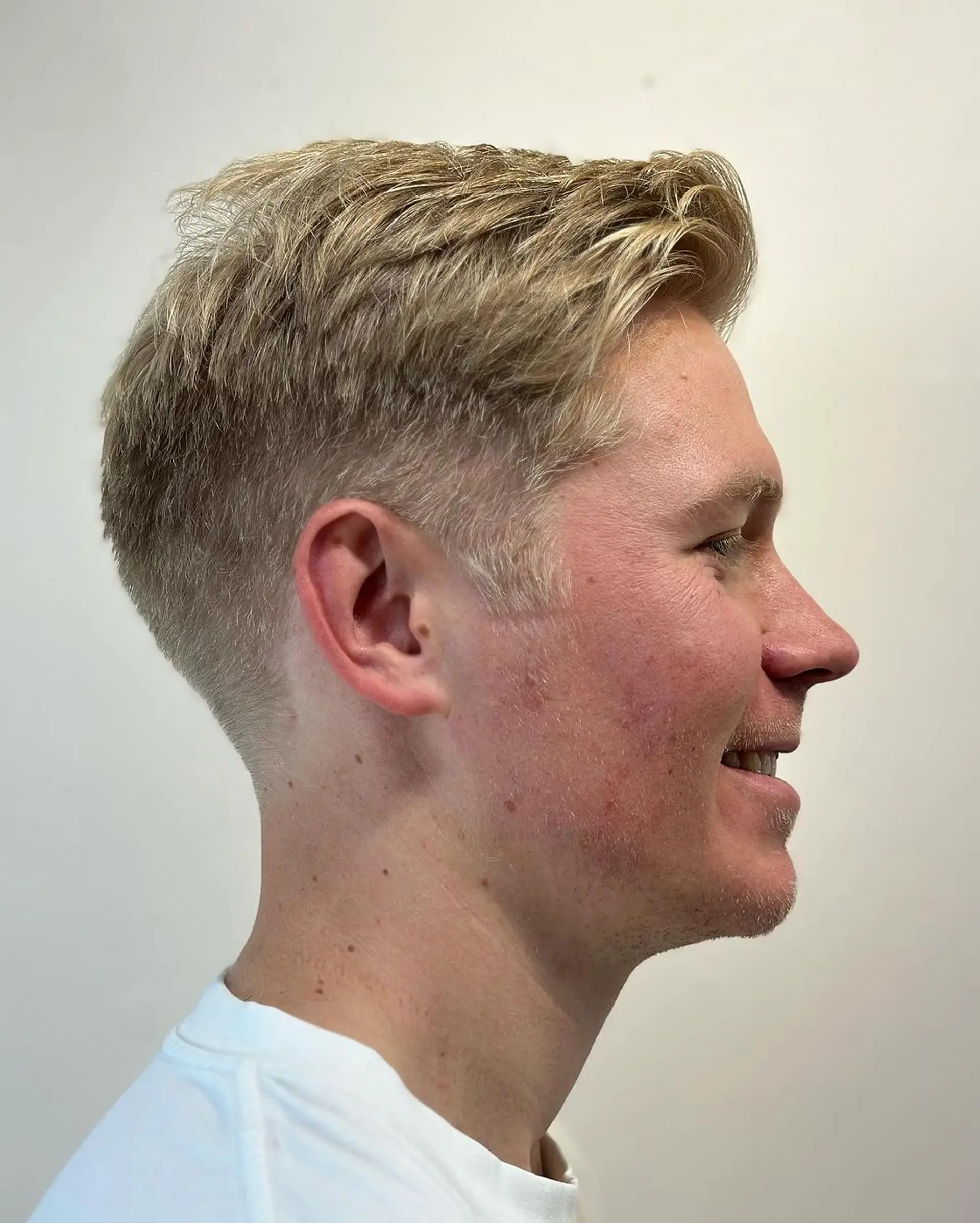 A sleek and short blonde hairstyle with tapered sides and a textured top, featuring a subtle side part. 3