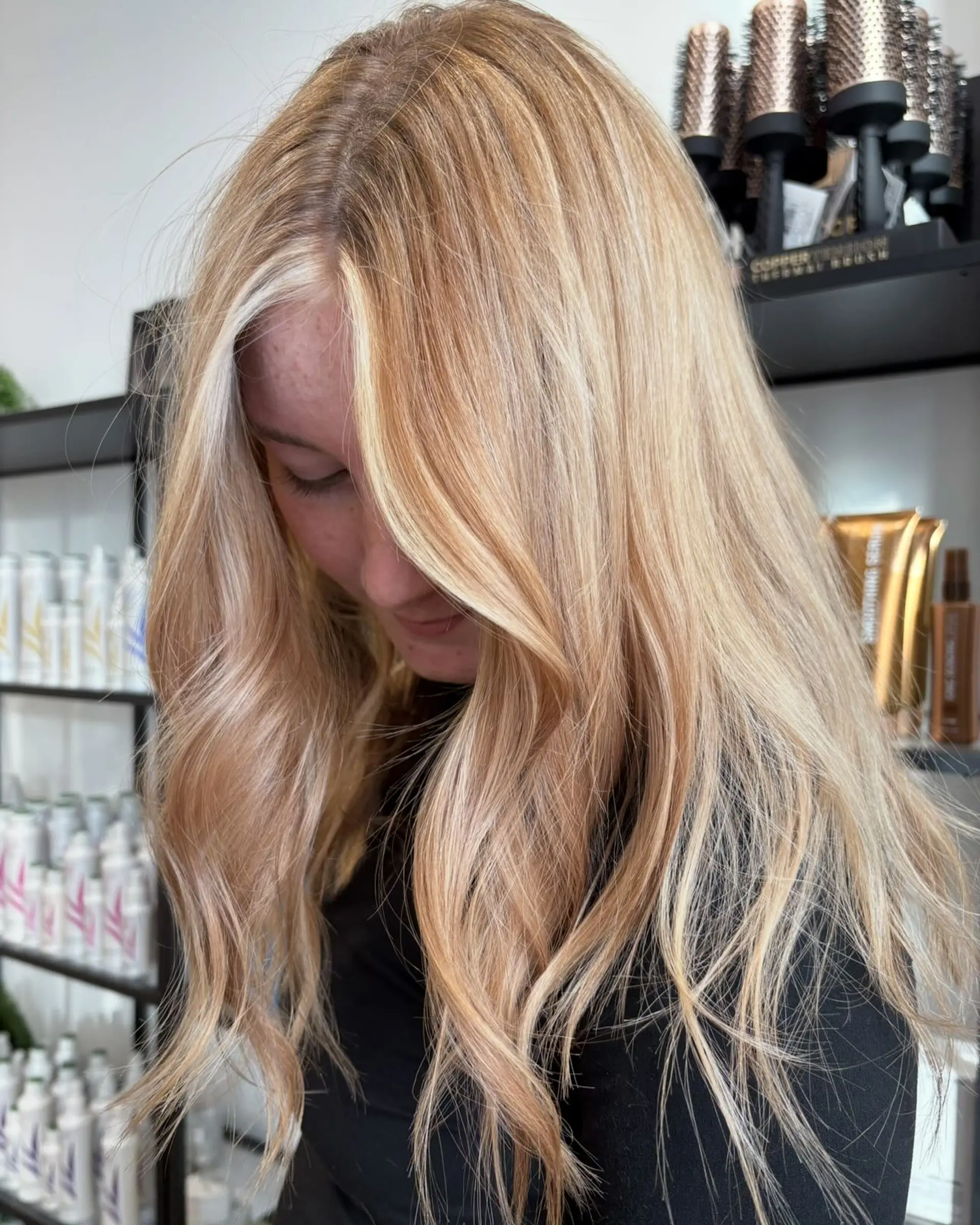 Long multi-tonal blonde hair with a bright face-framing money piece, styled into soft, loose waves. 1