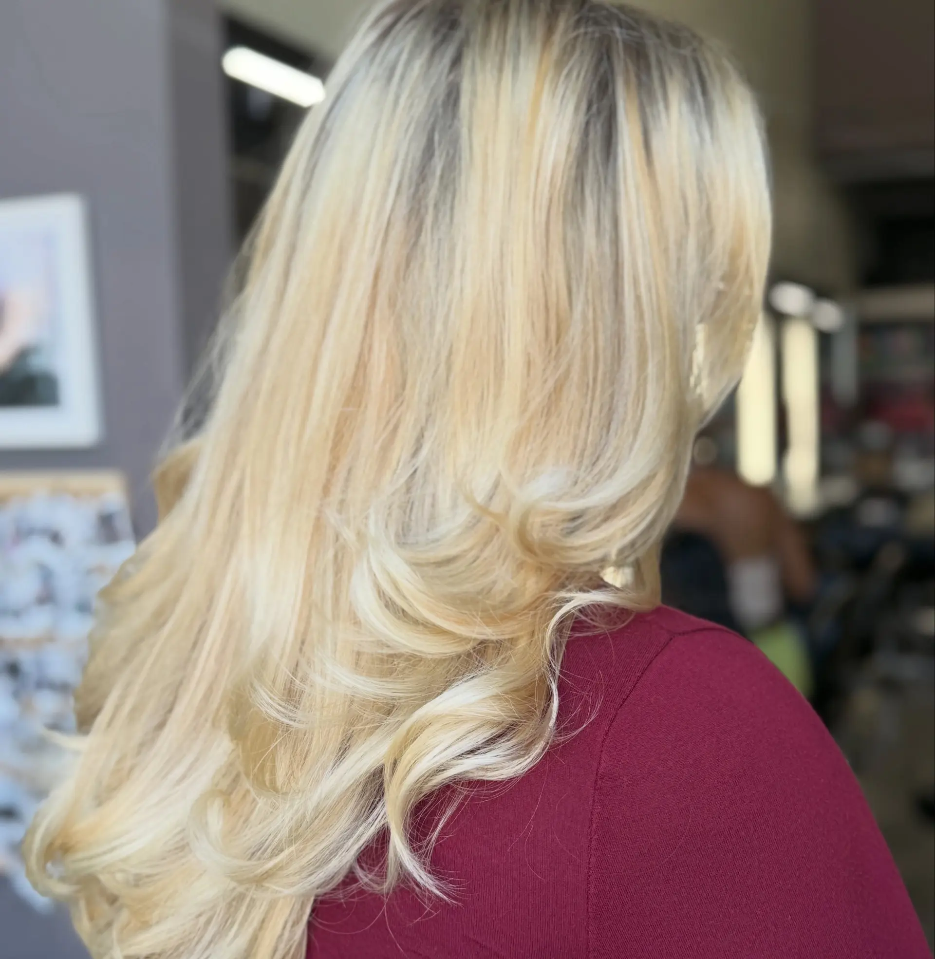 Long dimensional blonde hair styled into a smooth, bouncy blowout with curled-under and flipped ends. 1