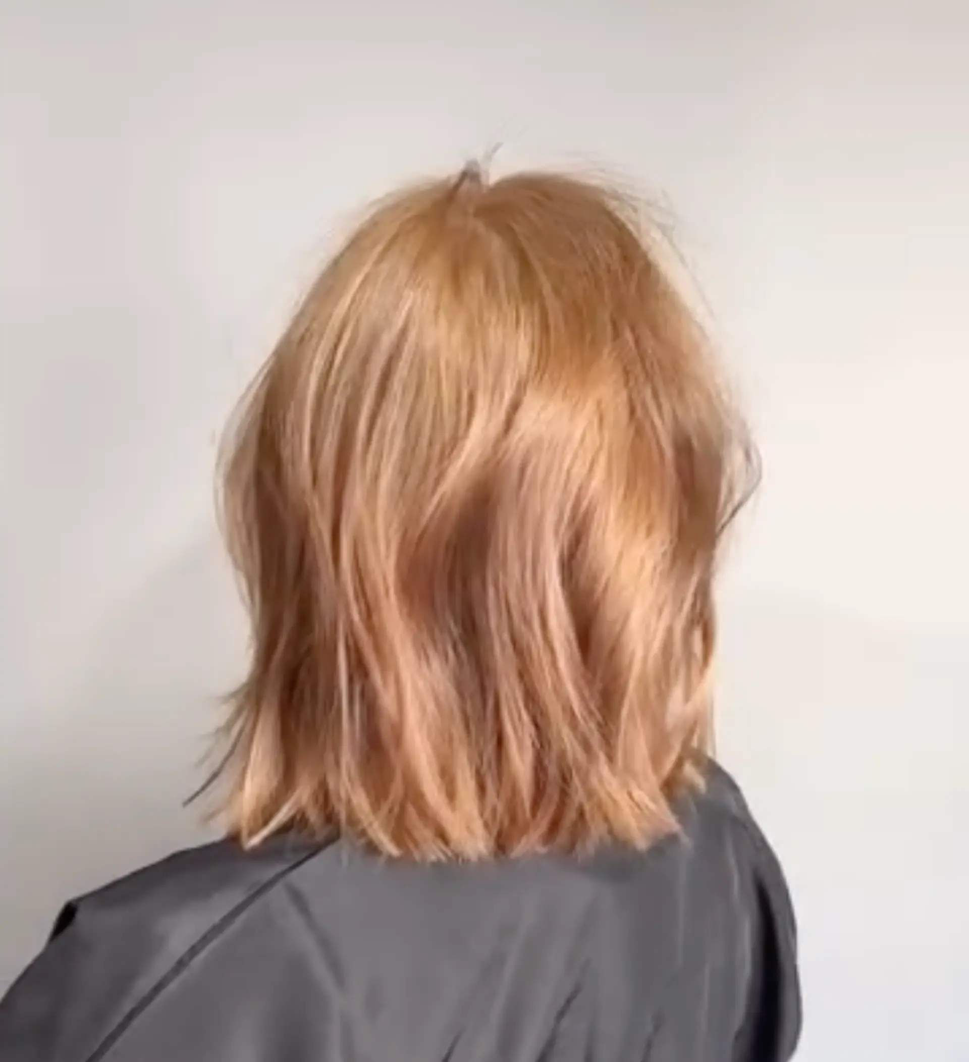 A medium-length, layered wavy rose gold bob with blunt ends and a middle part. 2