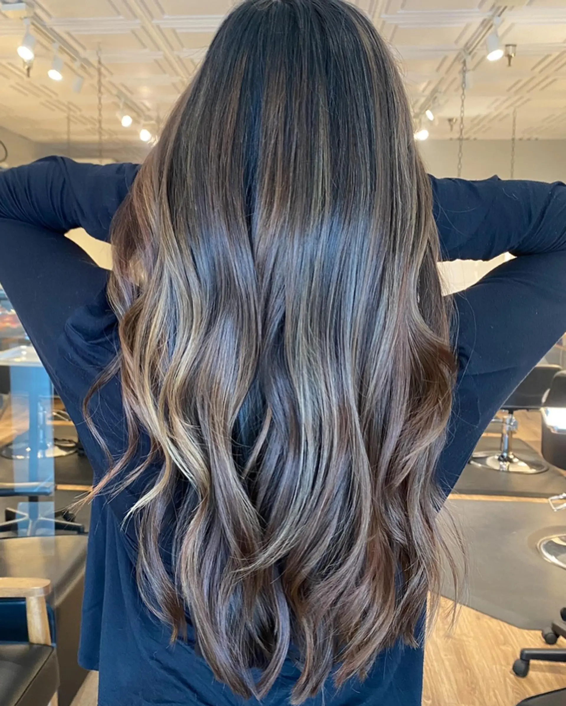 Long, dimensional brunette hair featuring fine balayage highlights and styled with soft, cascading waves. 1