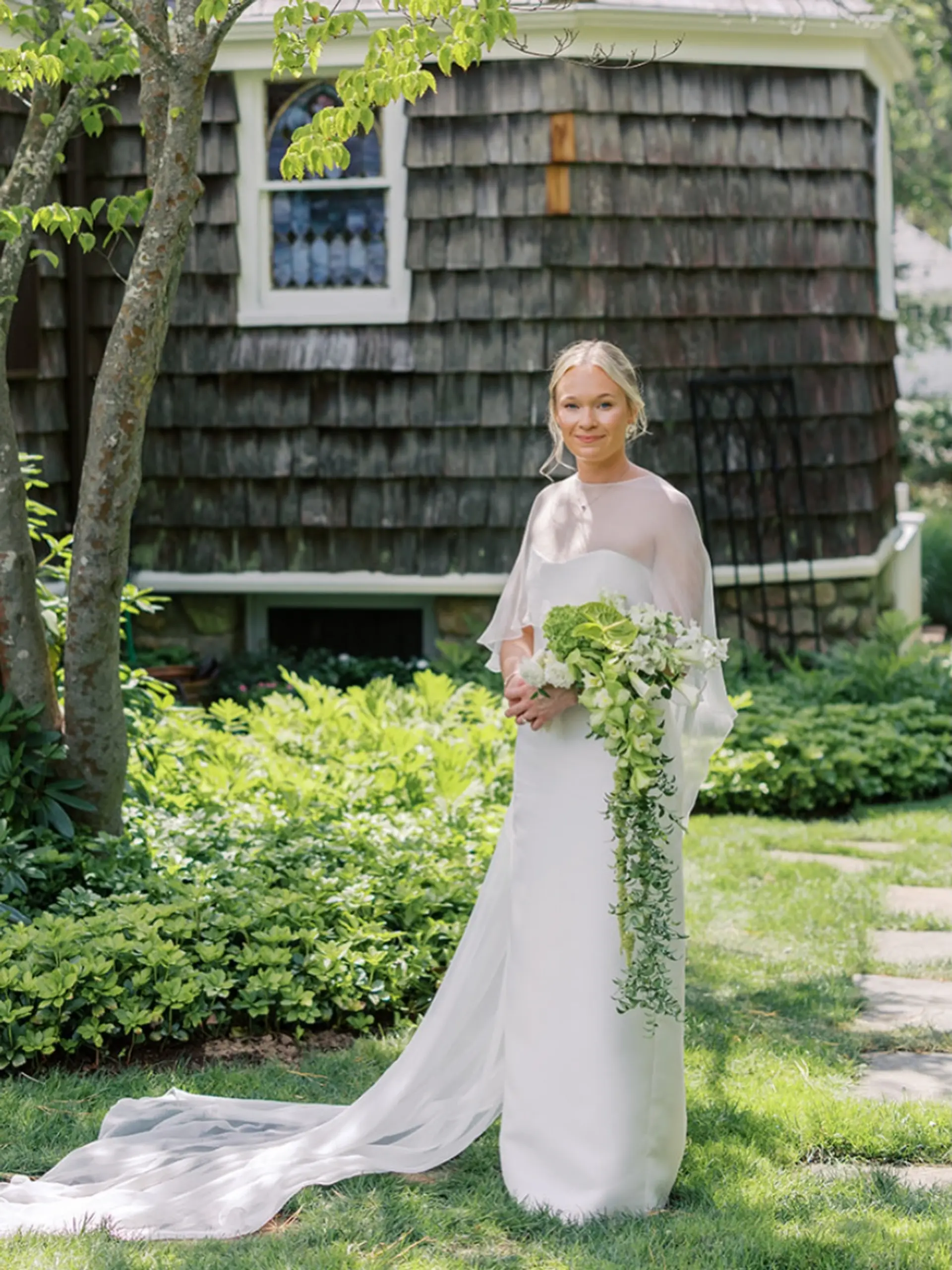 An elegant bridal updo with a clean center part and soft face-framing pieces. 1