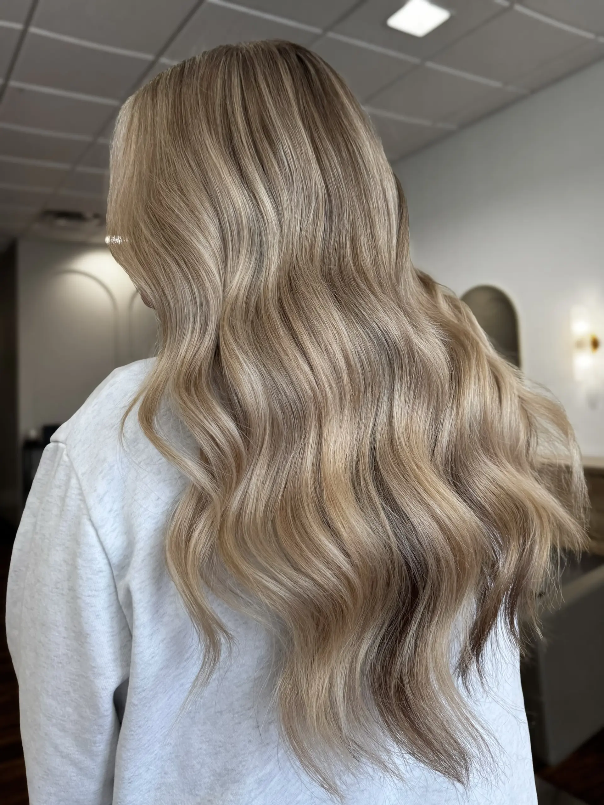 Long dimensional blonde hair styled into smooth, flowing waves. 1