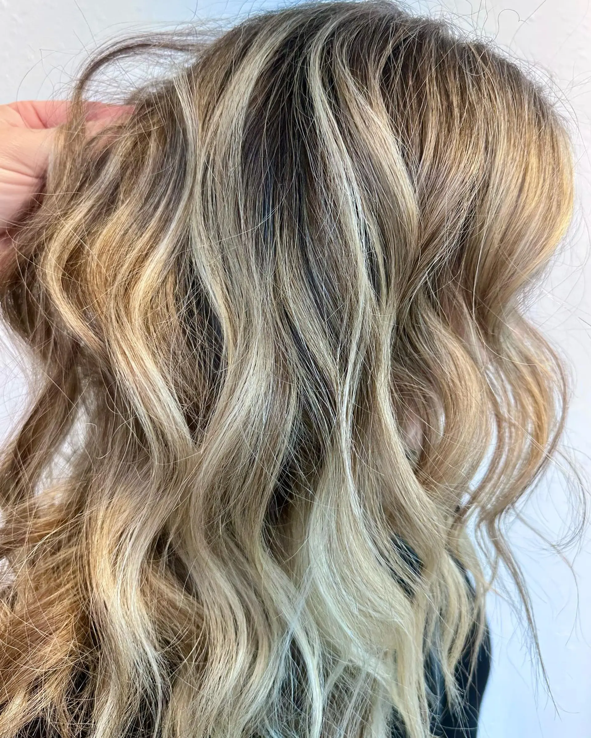Multi-tonal dimensional blonde foilyage with seamless root blending and soft, textured waves. 1