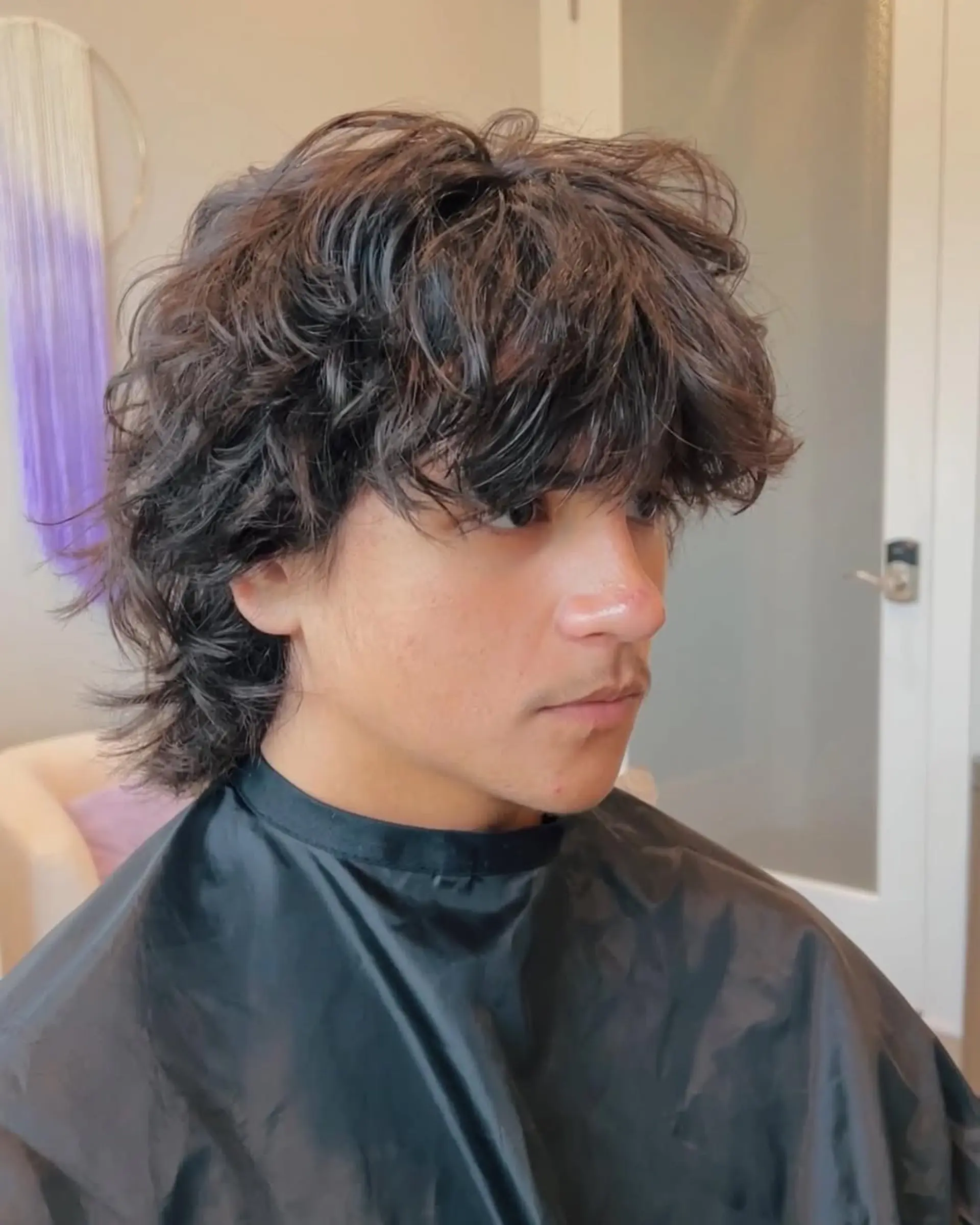 A trendy textured shag mullet with choppy layers, giving a voluminous top and longer, feathered ends at the back and sides, perfectly enhancing natural wavy hair. 1
