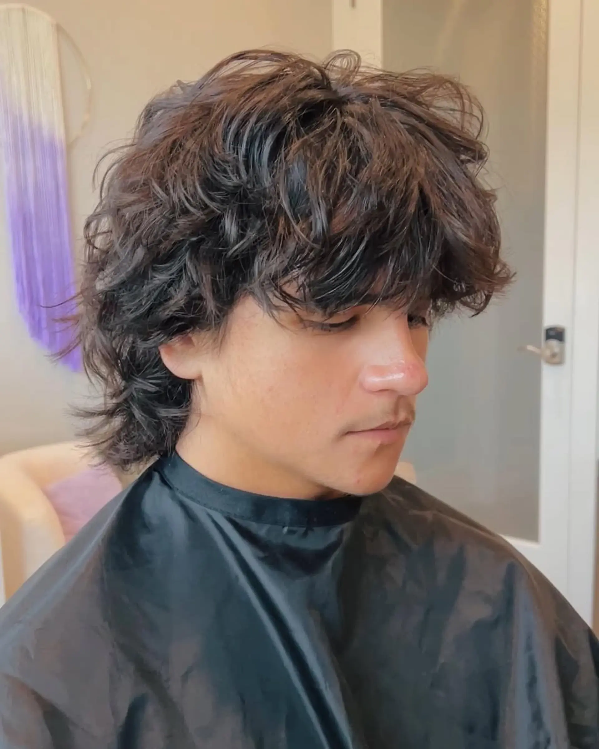 A trendy textured shag mullet with choppy layers, giving a voluminous top and longer, feathered ends at the back and sides, perfectly enhancing natural wavy hair. 2