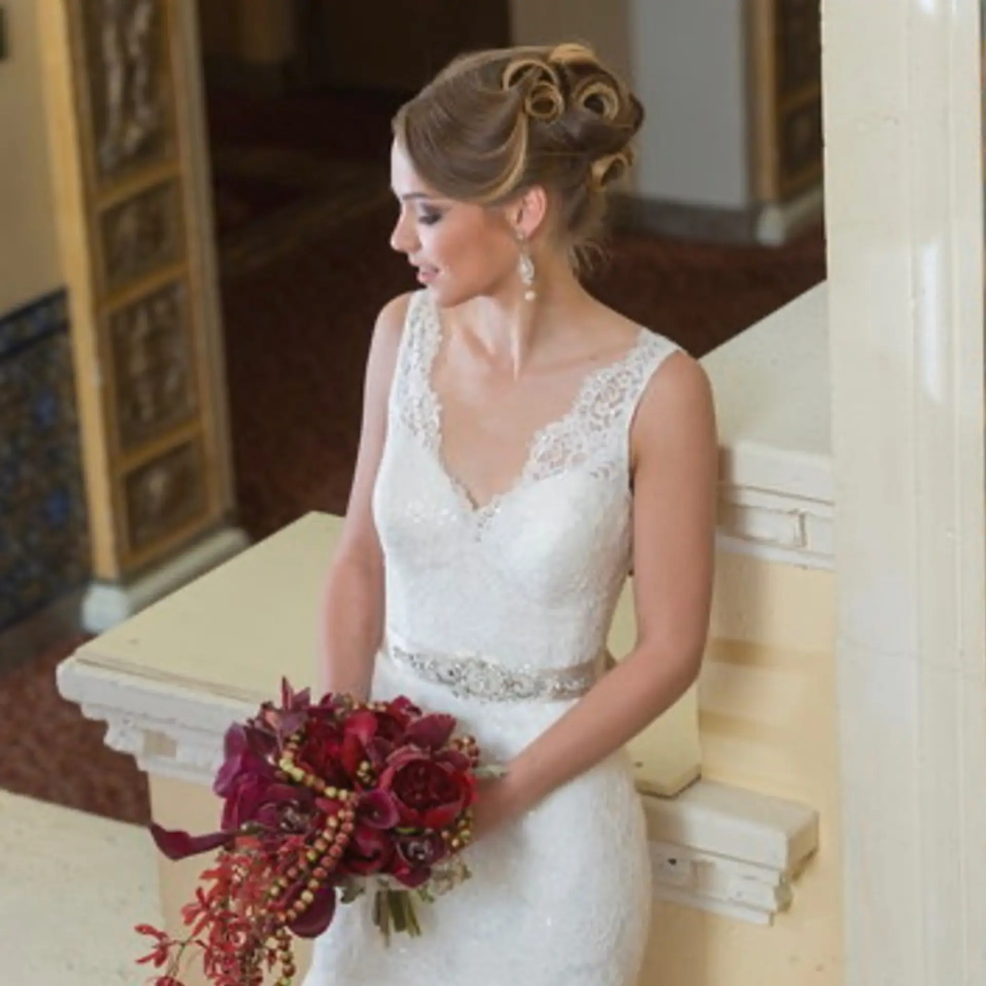 An intricate bridal updo featuring sleek sides and sculpted hollow curls pinned high on the crown. 1
