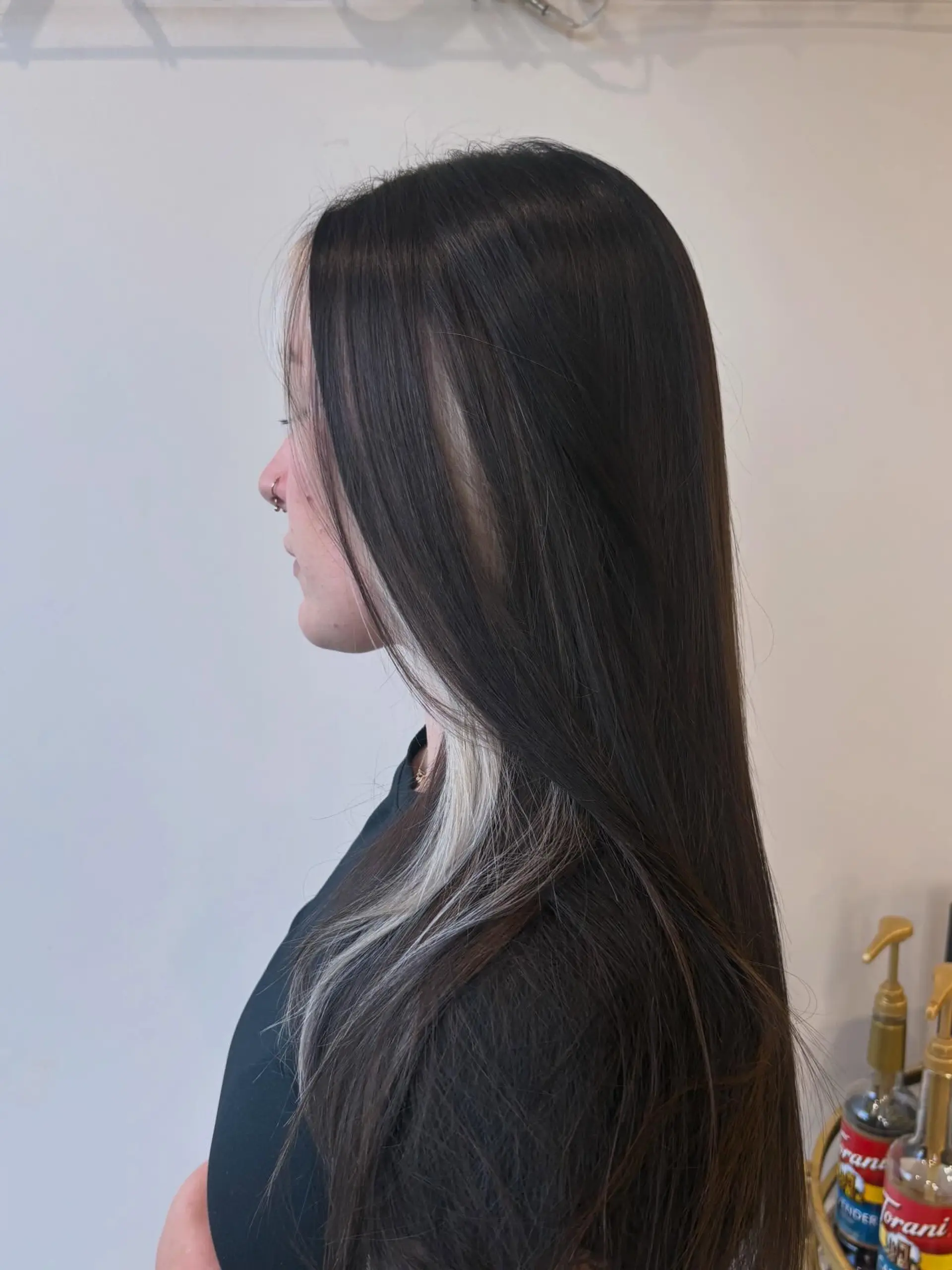 Long, sleek straight dark brown hair featuring high-contrast platinum blonde peekaboo highlights underneath and around the face framing sections. 1