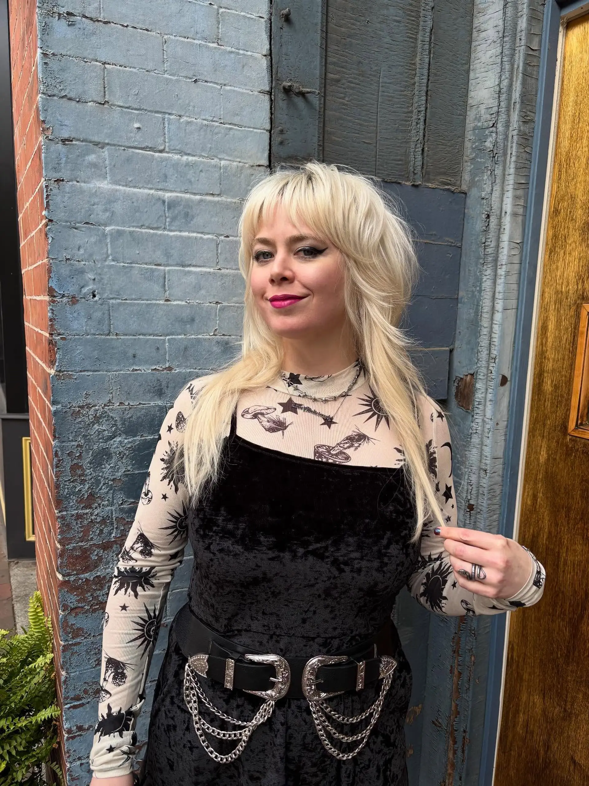 A textured bleach blonde modern shag mullet featuring wispy fringe bangs, heavily layered feathered crown volume, and long wispy lengths falling over the shoulders. 1