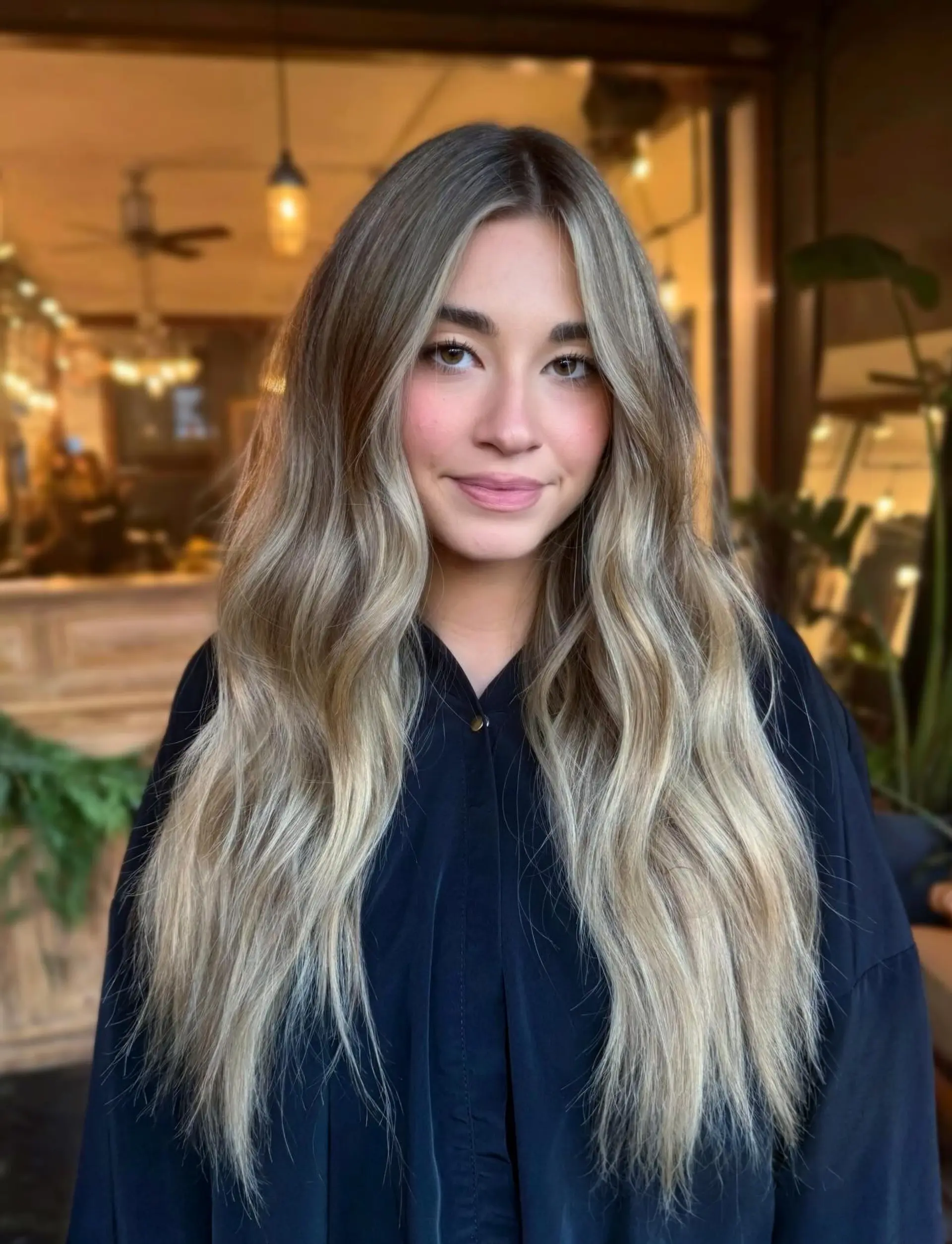 Long ash and beige blonde hair styled with soft, cascading waves and a classic middle part. 1