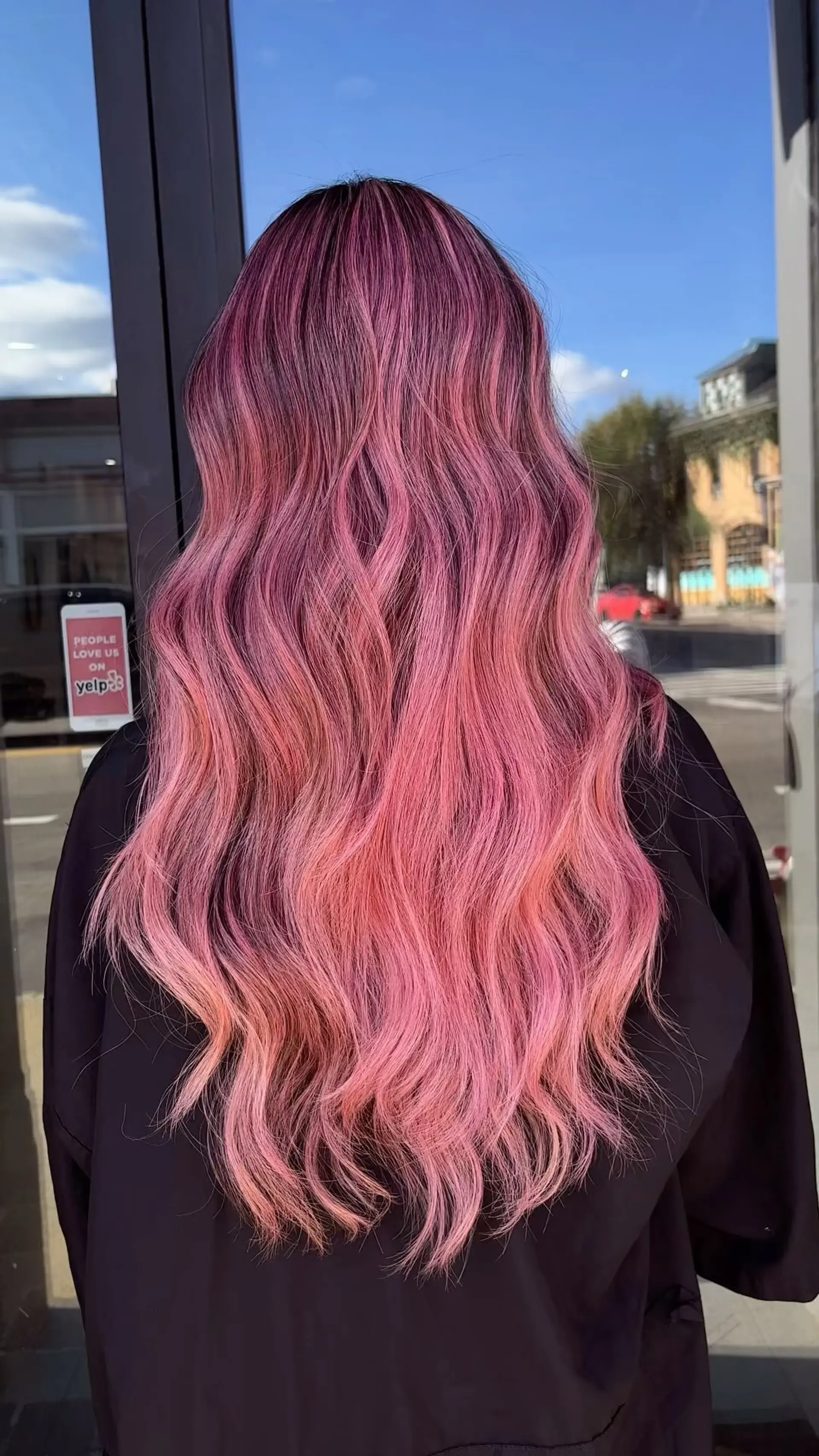 Long wavy hair featuring a seamless color melt from deep magenta roots into pastel bubblegum pink lengths. 1