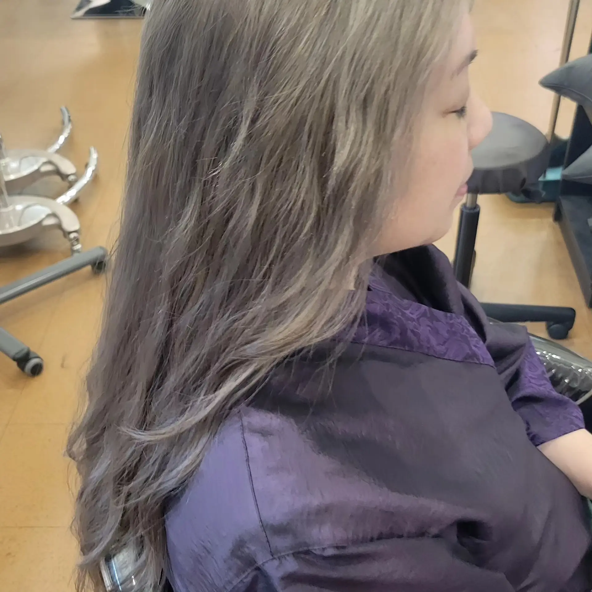 Long layered hair dyed in a cool-toned smoky ash blonde shade with subtle waves. 1